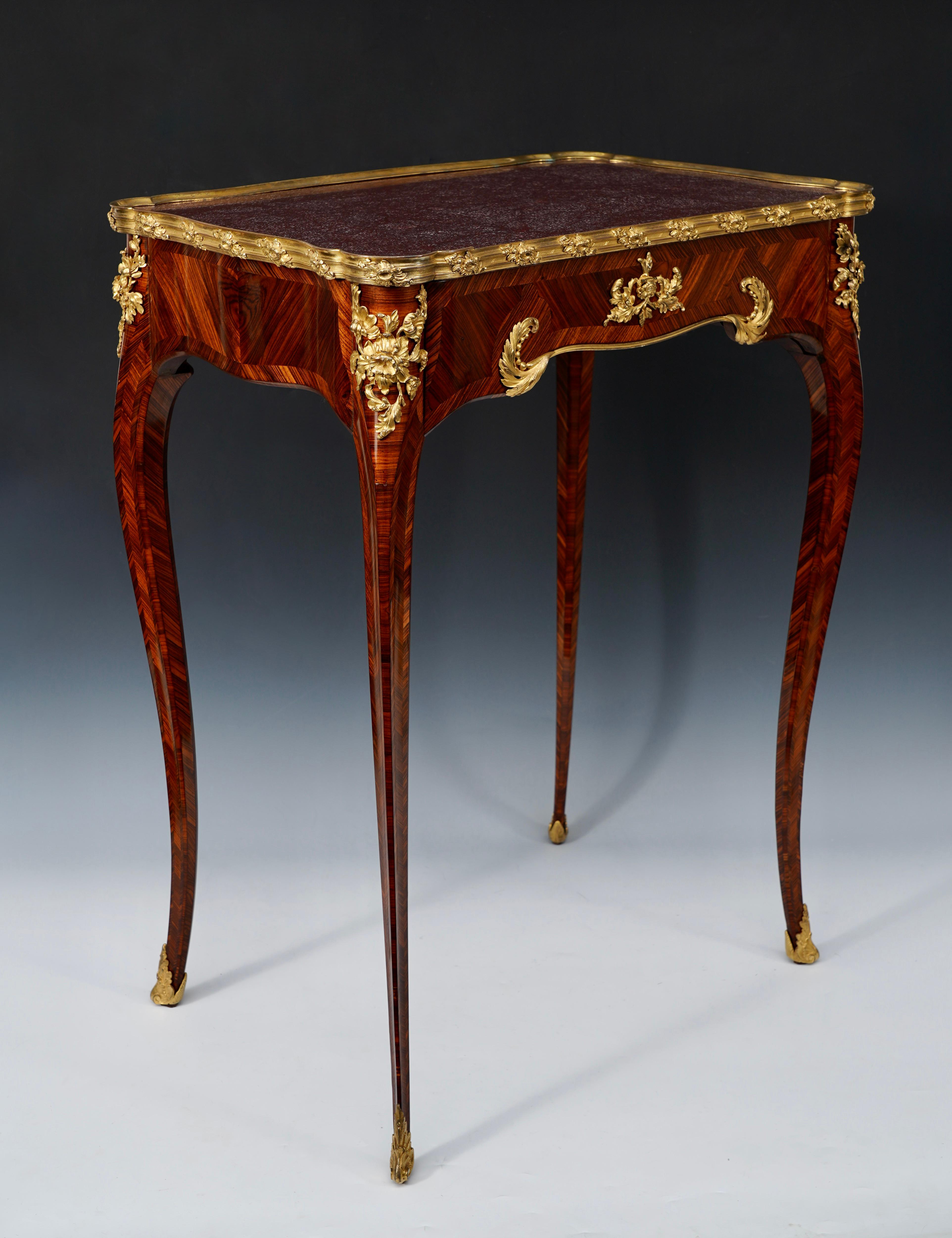 Stamped H. Nelson

Charming Louis XV-inspired scalloped-shaped writing table in kingwood veneer and decorated with a fine gilded and chiseled bronze mount. The tray, surrounded by a gilded bronze mold, is covered with an Egyptian porphyry top. It