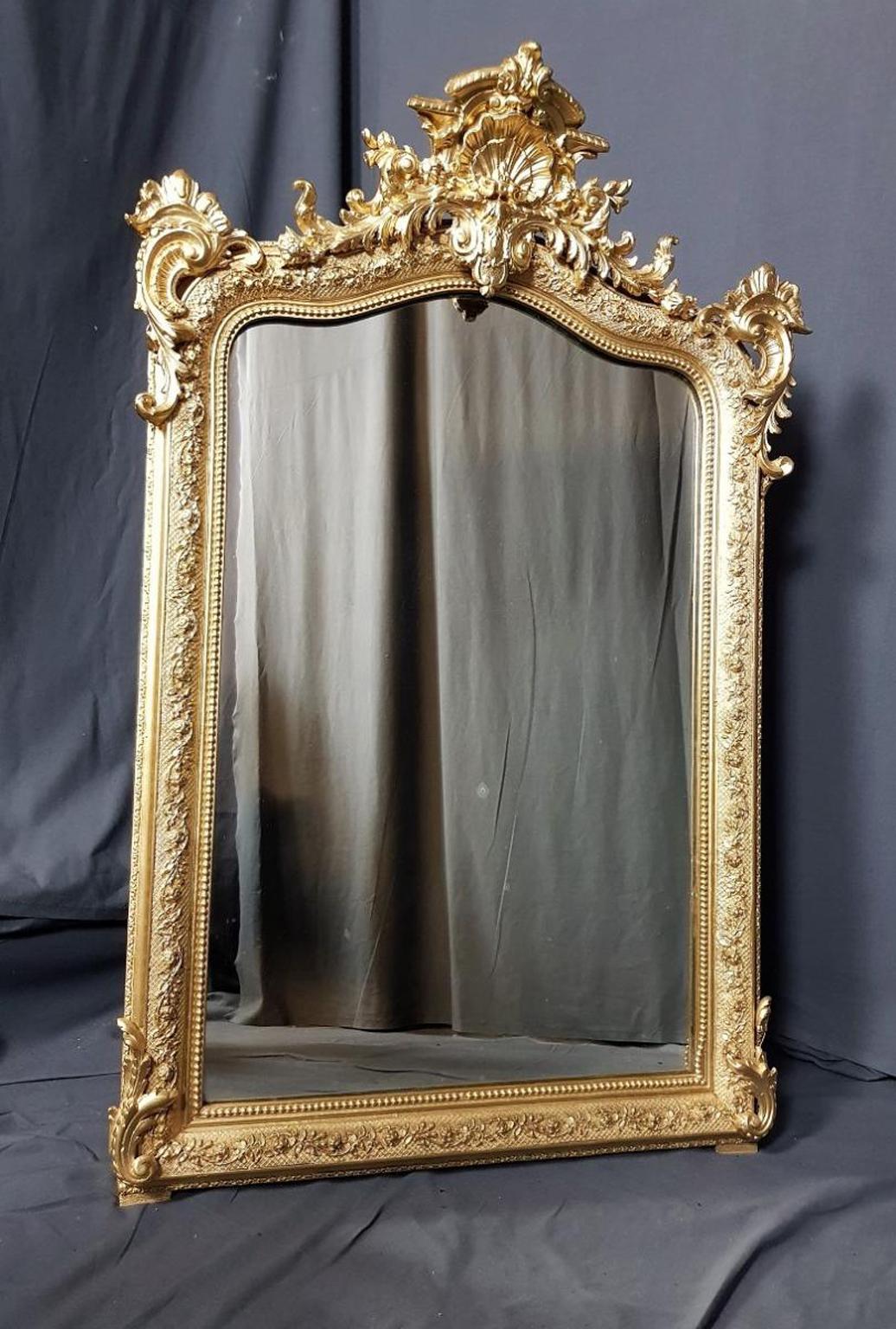 Gorgeous large size Golden Wall mirror in Louis XV style, made in giltwood and stucco. In an excellent general condition.
Very refine ornaments of volutes, guillochage on the pourtour, and a Louis 15th fronton.
France, circa 1869.