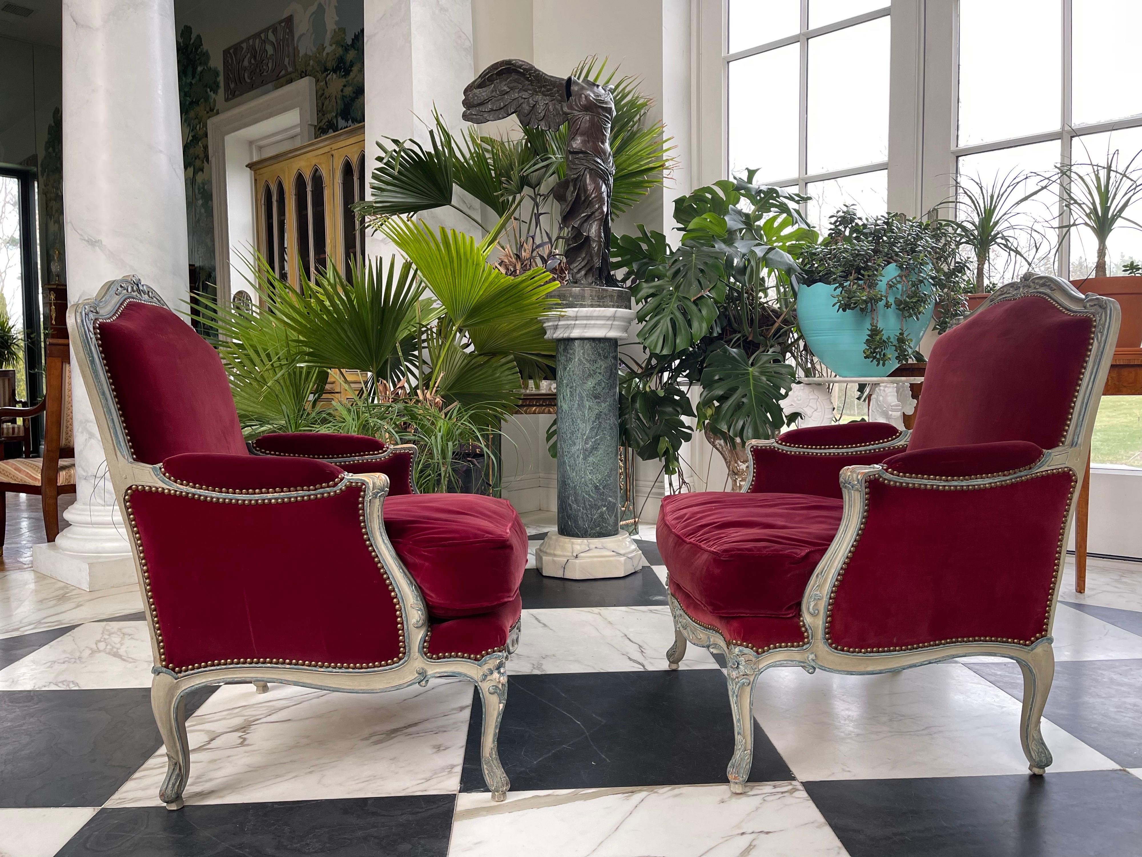 8 Louis XV style fauteuils. They are large in scale and are exquisitely hand carved with leaves and flowers out of beechwood and then painted in traditional grey and blue tones. The upholstery is a subtle burgundy cotton velvet, the cushions are