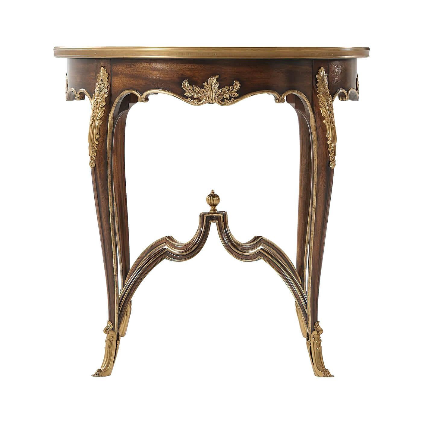 A fine and delicate French Louis XV style mahogany and gilt accent table, the brass bound mother of pearl inlaid and line strung okum veneered top above an undulating hand carved acanthus scroll apron, on slender cabriole legs with fine brass mounts