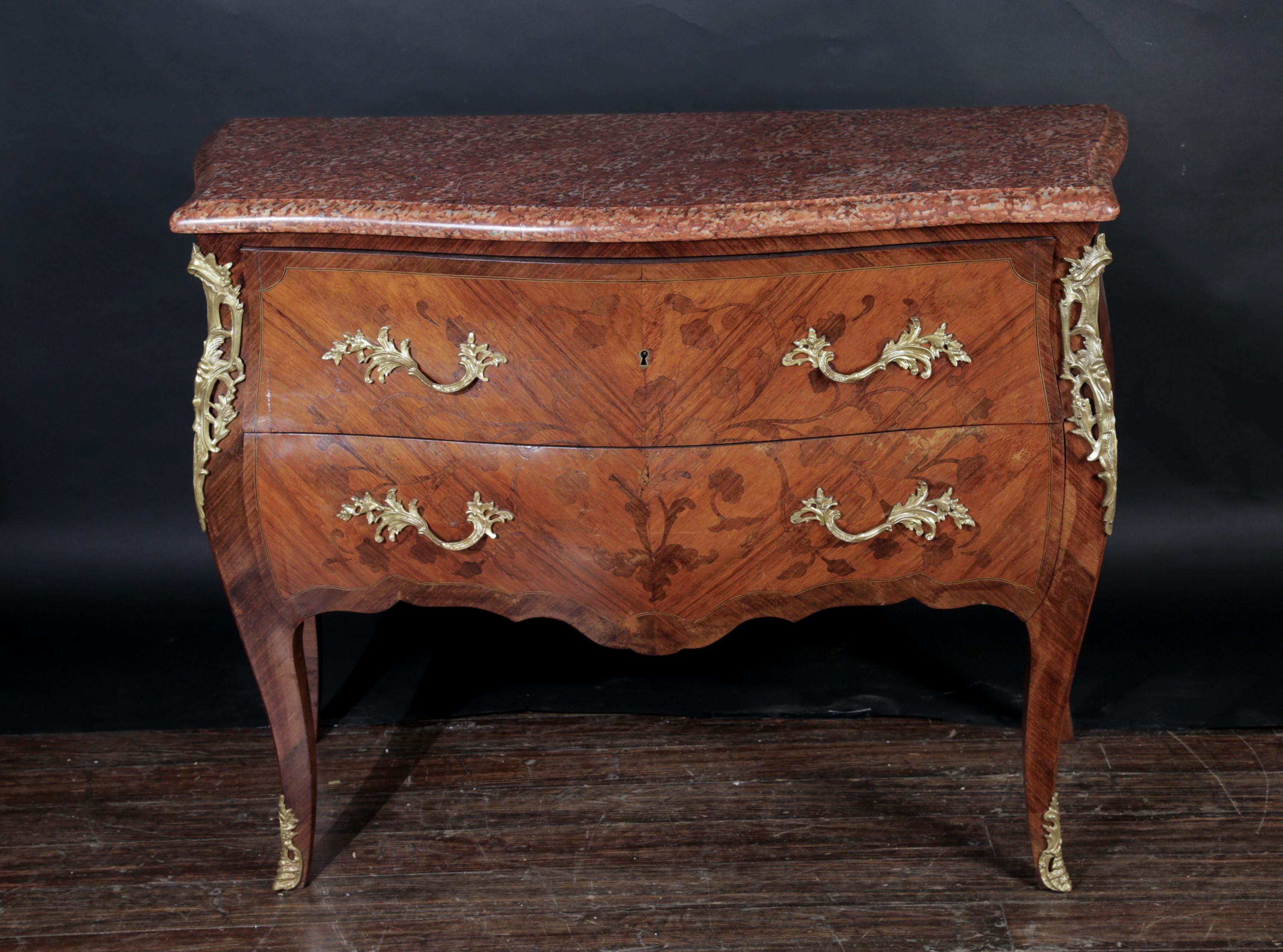This beautiful Louis XV Bombe commode dates back to the 19th century and features elaborately inlaid marquetry work with a floral design that covers the two front drawers as well as both sides. The term bombe is a translation from the French word
