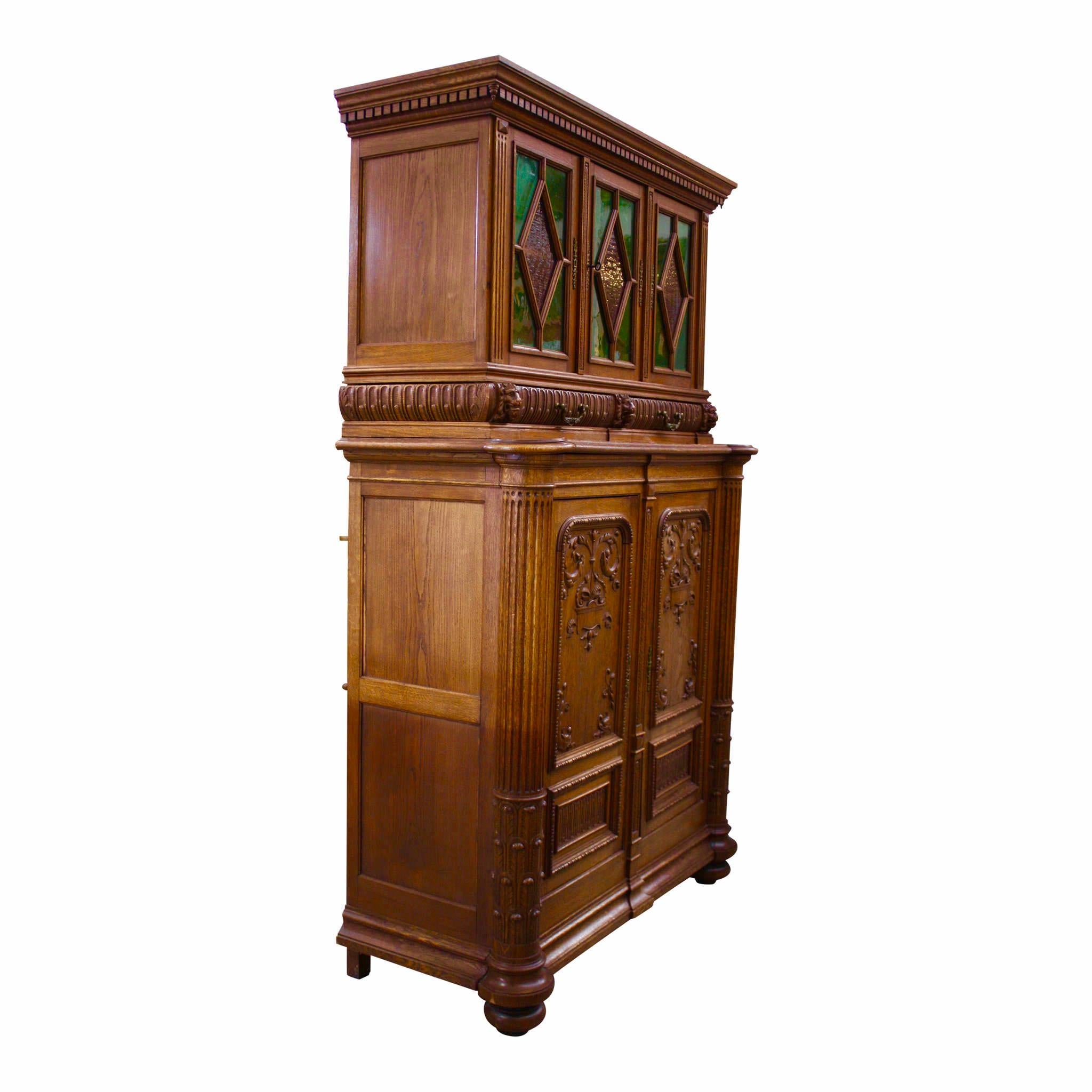 This stunning buffet incorporates the warm tones of oak paired with the rich shades of green and rose glass. The buffet separates into upper and lower cabinets. The upper cabinet features crown molding with dentil trim, three doors with glass panes,