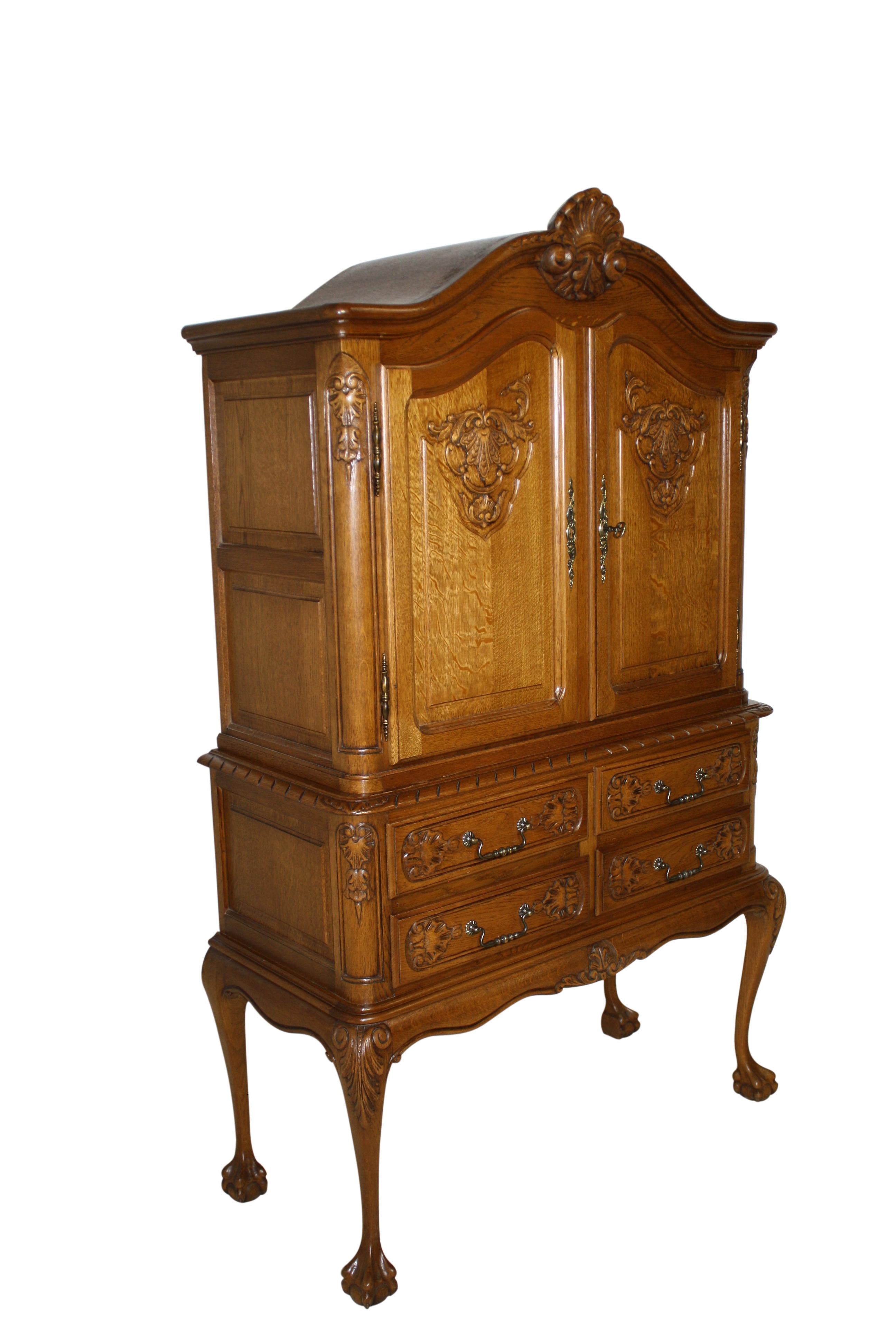 The soft curves of an arched bonnet cornice embellished with a central carved shell, rounded corners, and a scalloped apron are featured in this elegant cabinet, which is raised on long, slender cabriole legs that terminate in ball and claw feet.