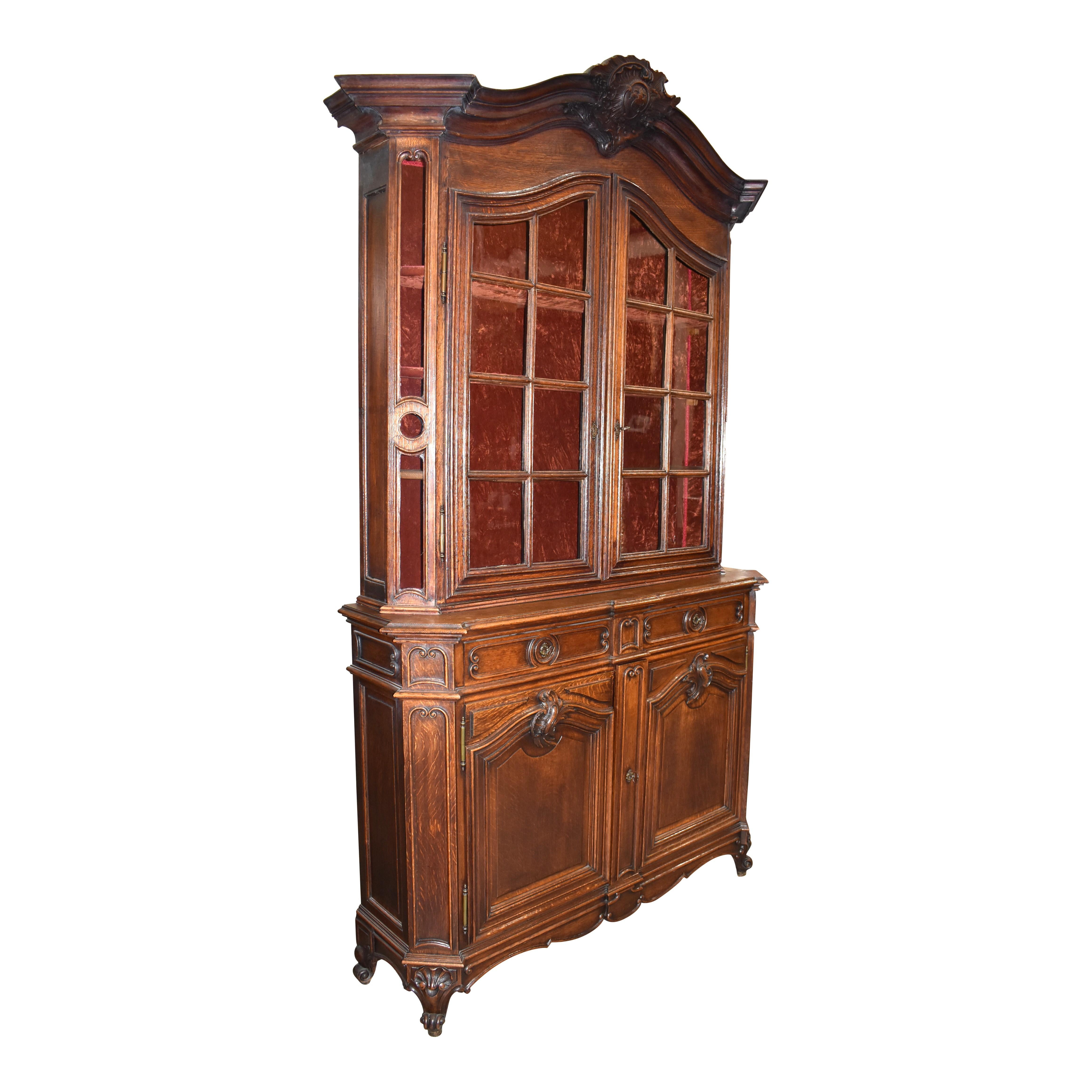 The definition of elegance, this stunning Louis XV display cabinet from the late-18th century is crafted from European oak with exceptional carvings and graceful lines. The arched bonnet is crowned with a substantial carved shell enclosing a