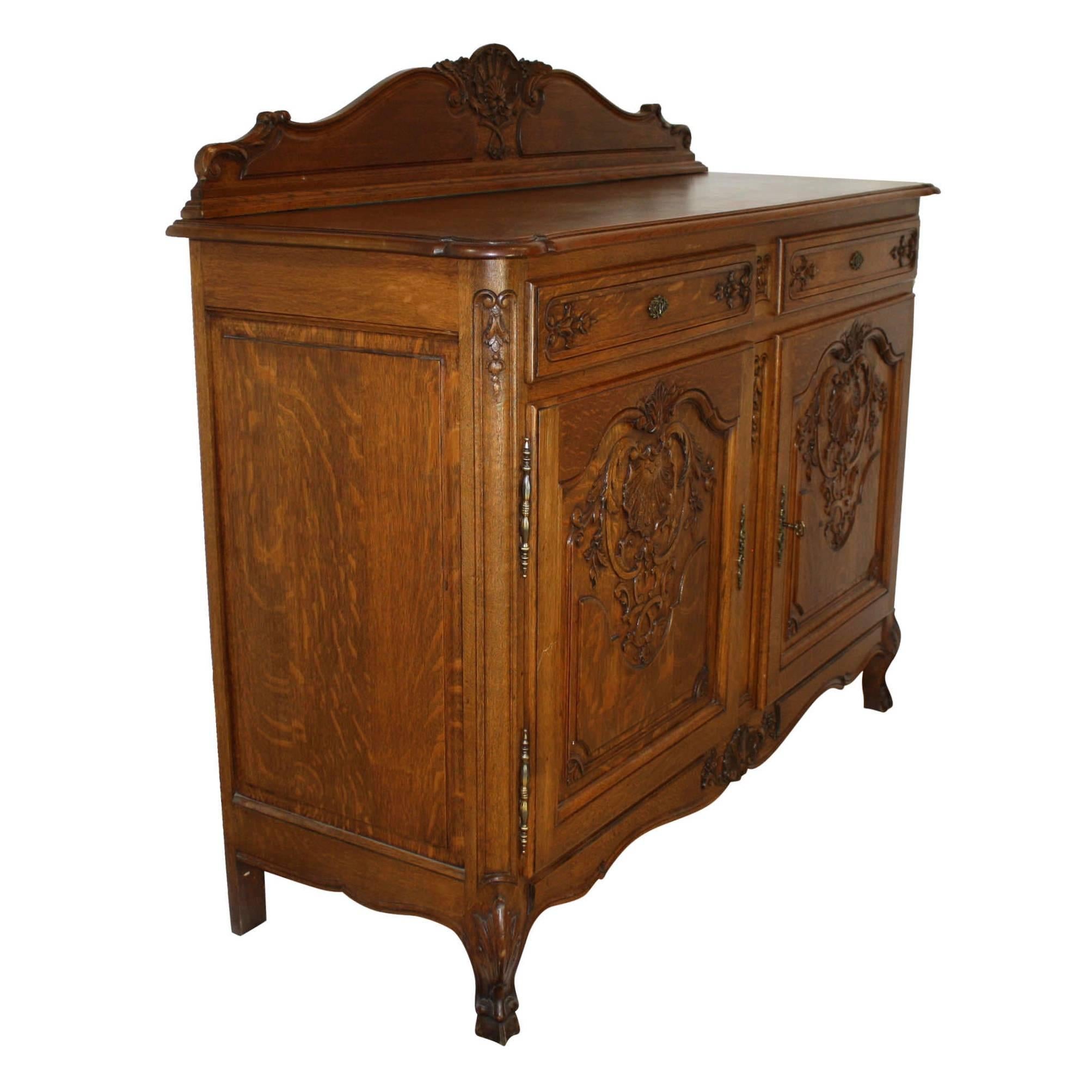 Fine craftsmanship and high quality, quarter sawn oak with pronounced medullary rays are showcased on this stunning Louis XV server. The server features beautiful shell and floral carvings on a scalloped backboard, apron, double drawers, and a pair