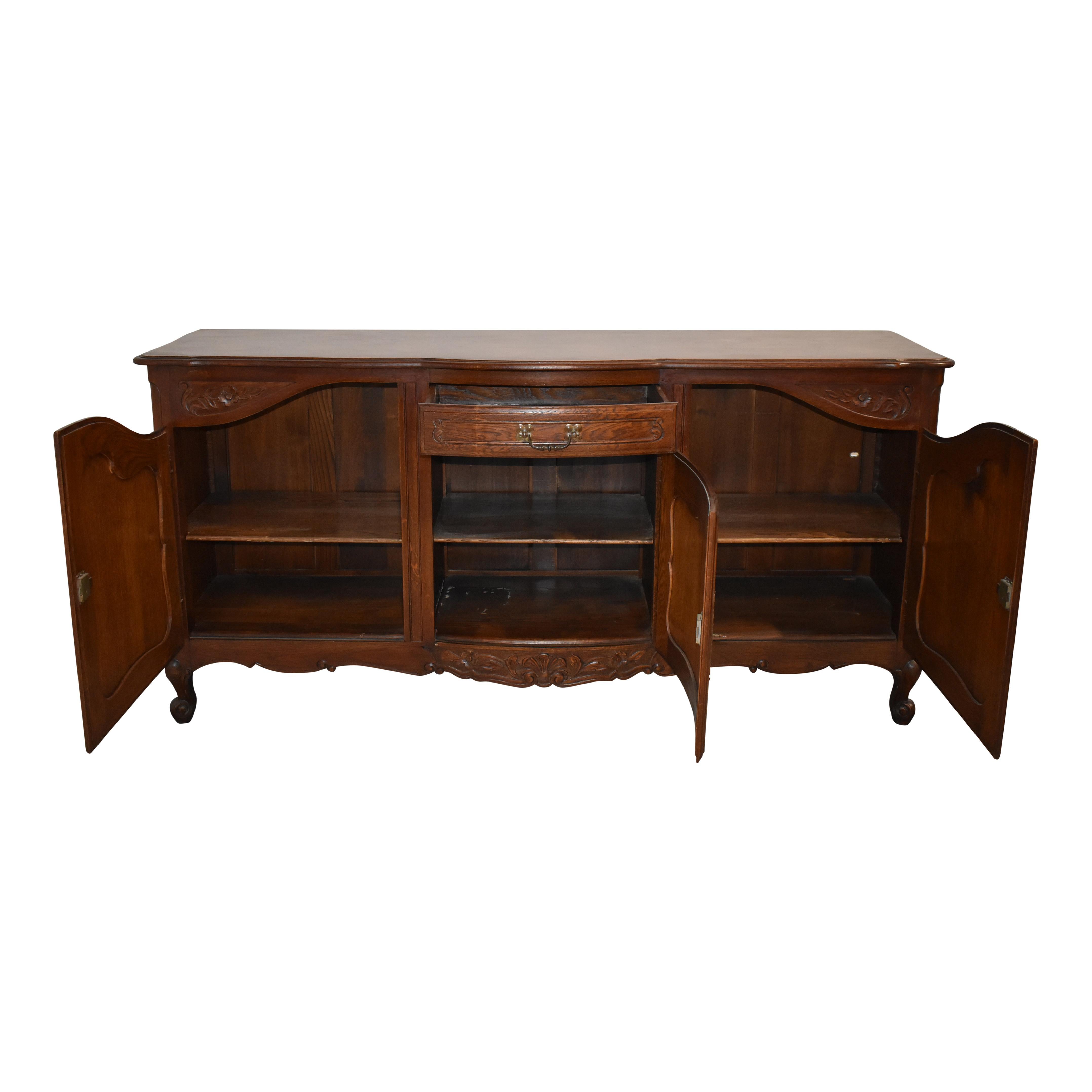 With a beautiful parquet top and graceful serpentine front, this oak sideboard features a central drawer with raised panel doors to the sides and below. A single key works all of the door locks. Dainty flowers are carved above the side doors and