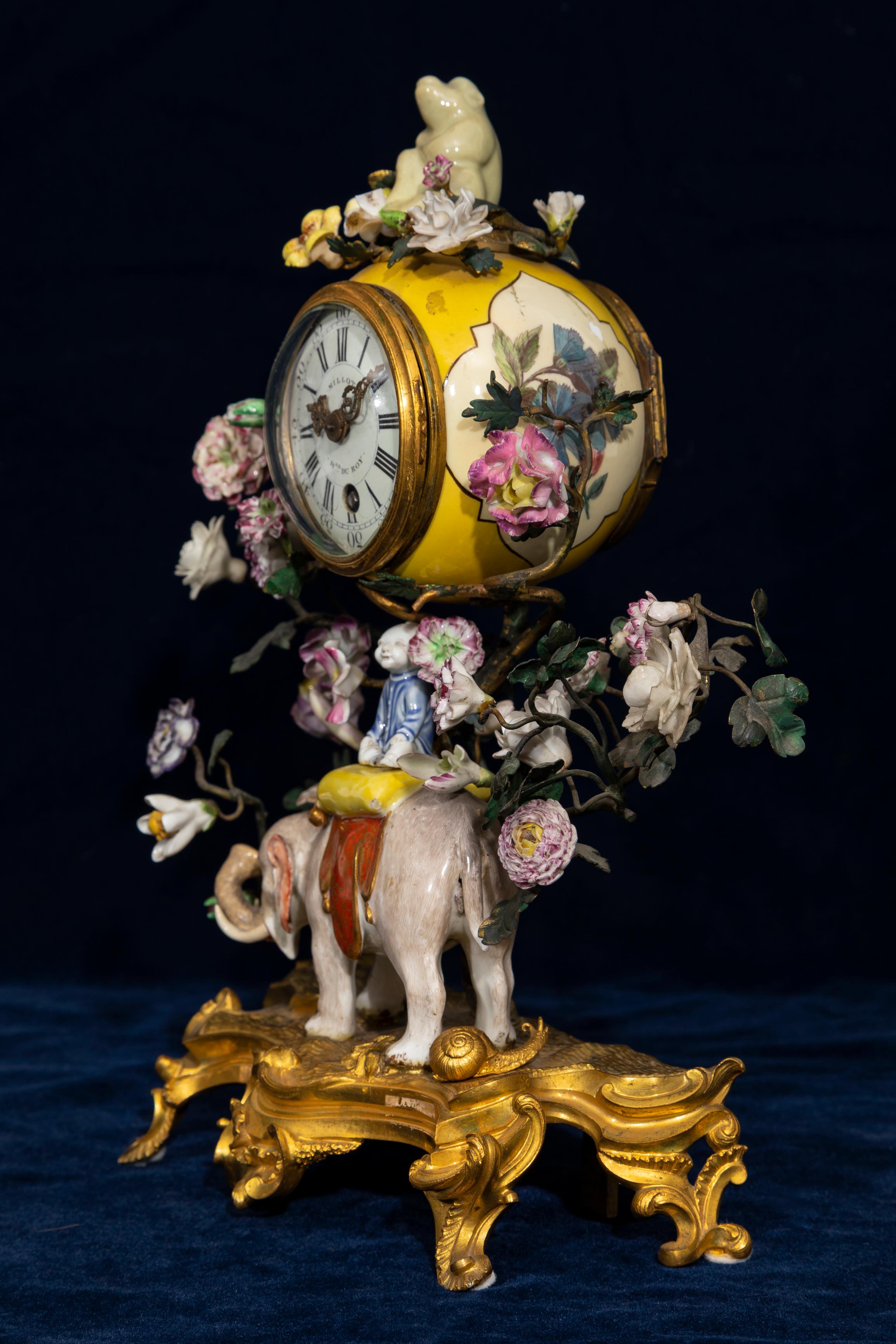 An Exceptionally Rare 18th Century Louis XV Ormolu Mounted Meissen Porcelain Chinoiserie Elephant, Snail, and Flower Mantel Clock. The clock drum is painted with floral reserves on a yellow-ground porcelain case, surmounted by a seated monkey