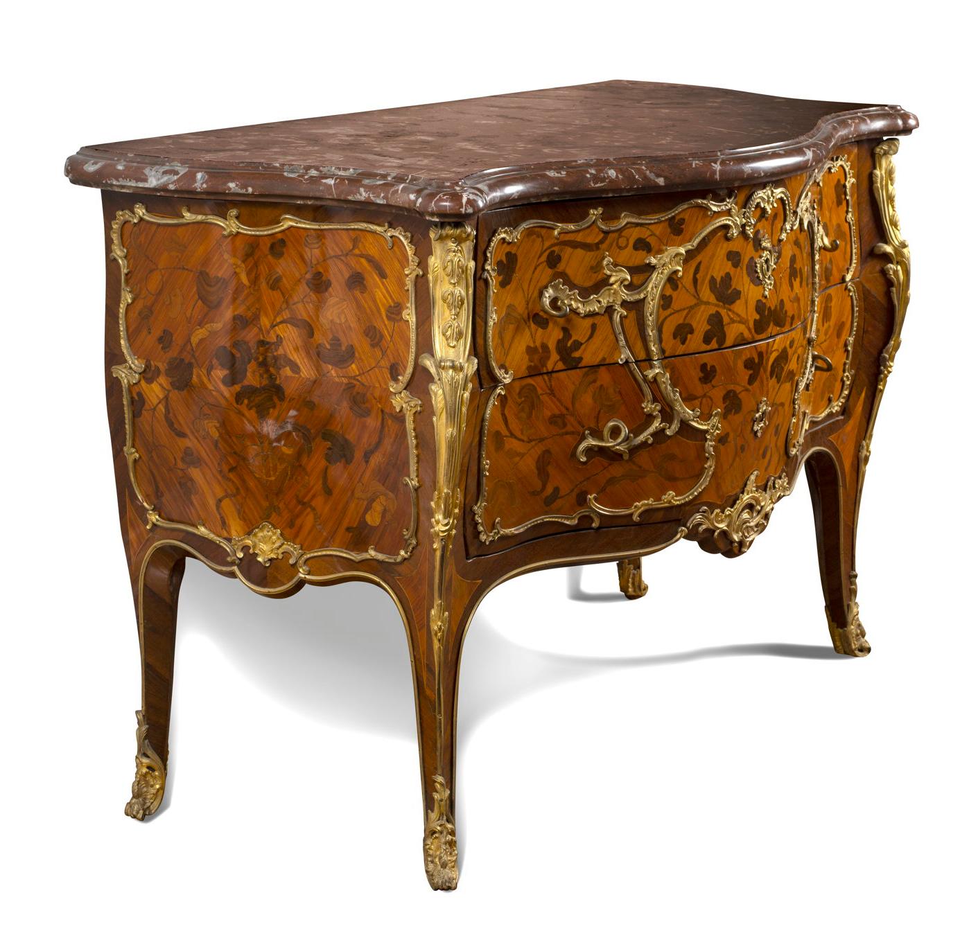 The serpentine molded ‘rouge royal’ marble above two long bombé-shaped drawers ‘sans traverse’ inlaid with bronzes and floral sprays, the sides decorated similarly, on splayed legs, the angles headed by floral-cast clasps and reaching to floral-cast