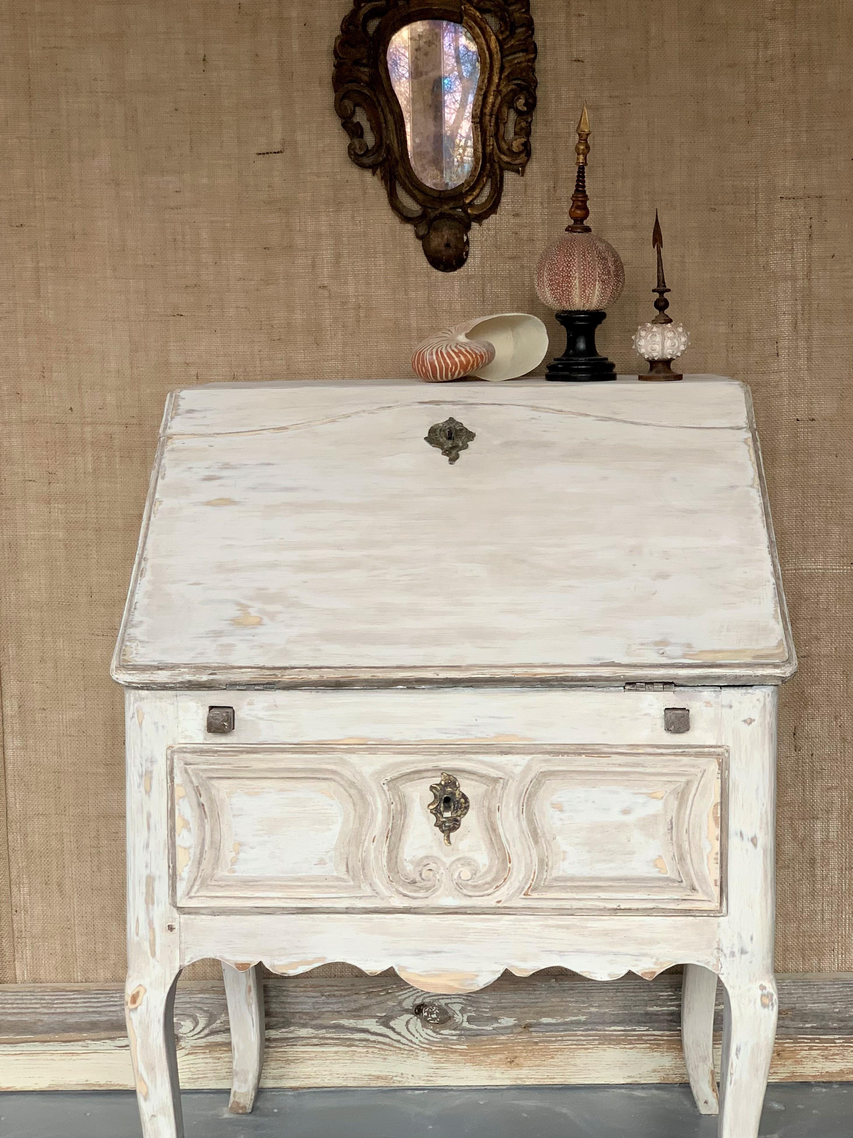 A charming and early French drop-front desk, Louis XV period, circa 1750, the cream painted exterior with a single carved-front drawer below an enclosed writing surface in blue painted finish. The interior retaines its original drawers and cubby