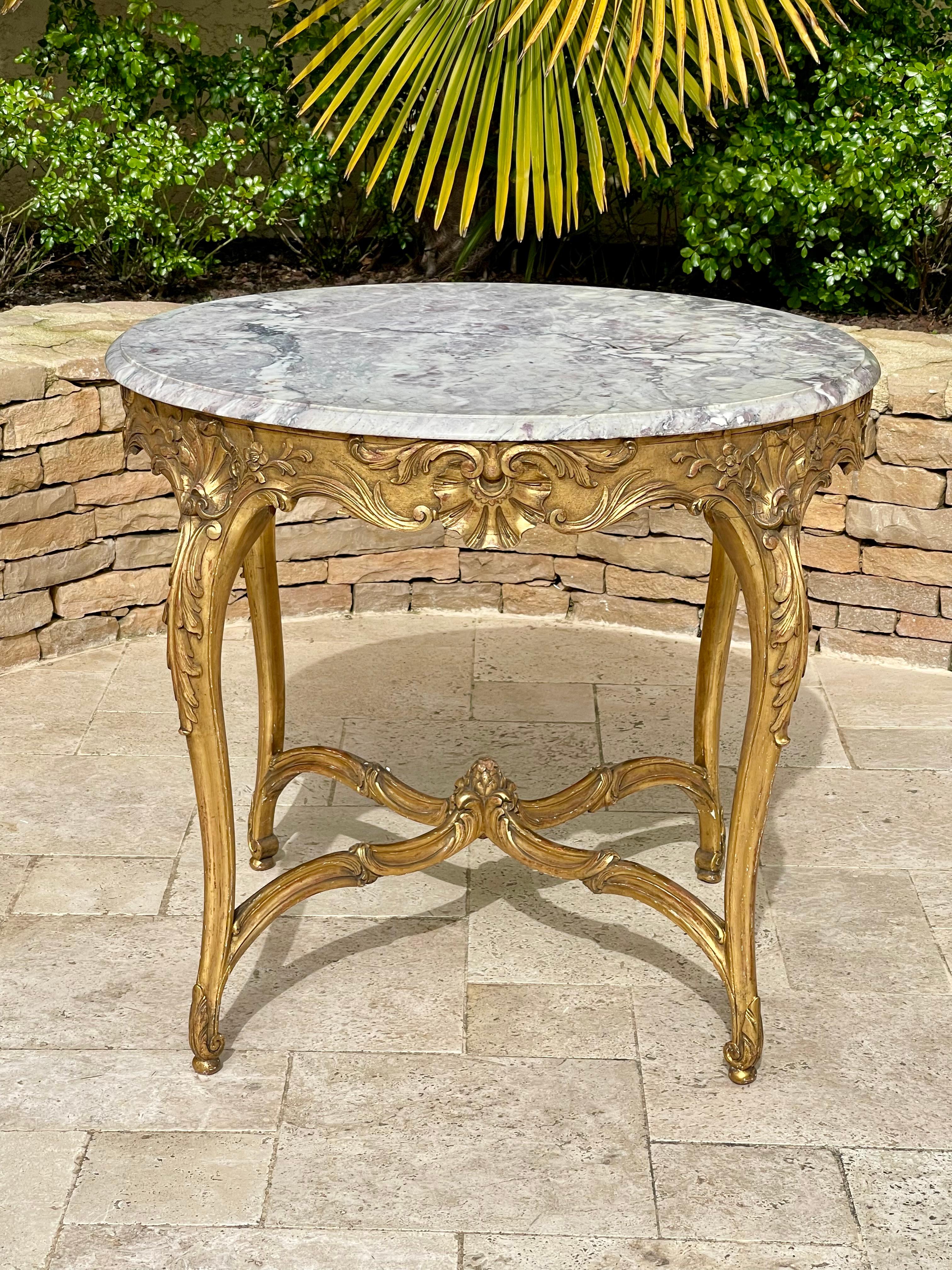 Très joli guéridon de style Louis XV en bois doré à 4 pieds en rocaille reliés par une entretoise. Les 4 faces sont bien décorées avec à chaque fois une belle coquille Saint-Jacques au centre. Dessus en marbre avec bec de corbin Fin du 19e siècle