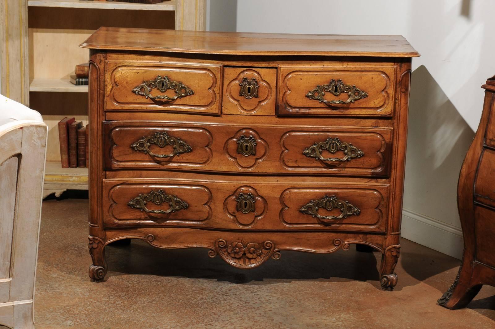 A French Louis XV period walnut five-drawer commode from the mid-18th century, with serpentine front. Born in the early part of the reign of King Louis XV, this French walnut commode features a planked top with beveled edges, sitting above five