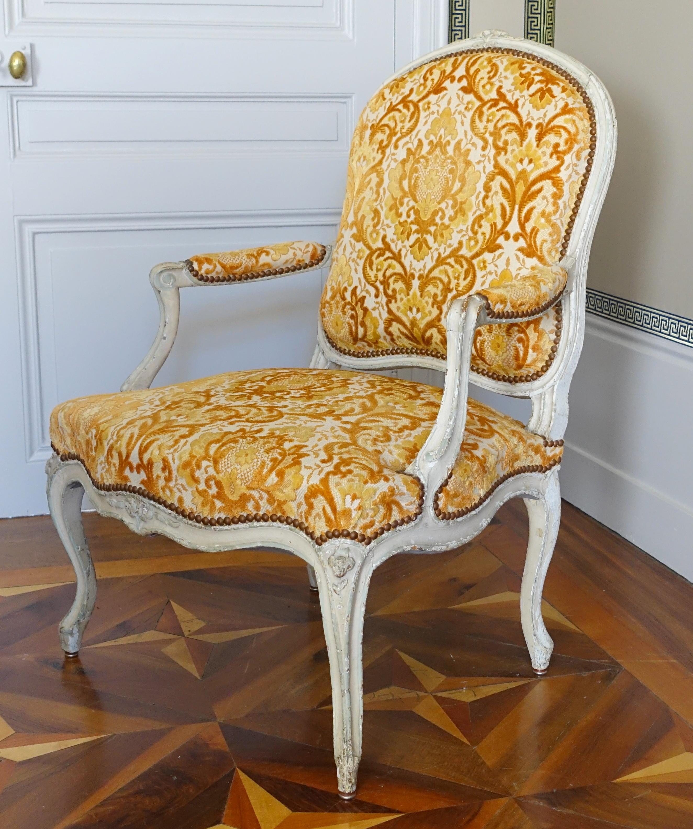 Fino sillón de época Luis XV de madera lacada llamado a la Reine, recubierto de terciopelo gofrado amarillo anaranjado. Siglo XVIII, hacia 1760.