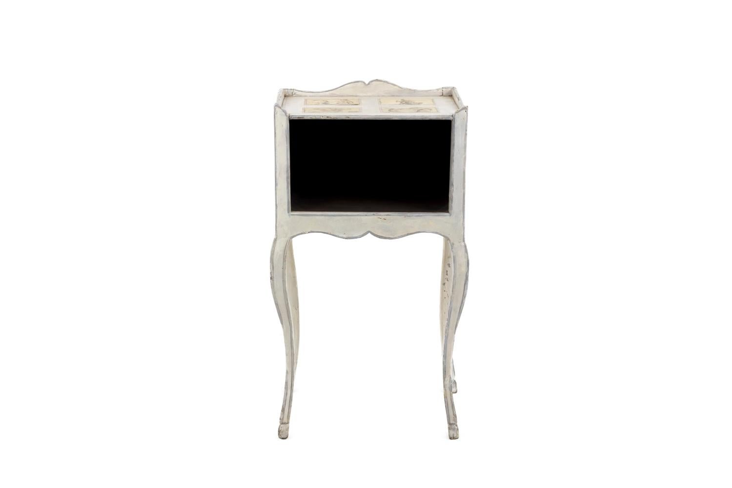 Louis XV period bedside table in white lacquered wood standing on four cabriole legs and front opened with a compartment.
Scalloped apron and tray edge.
Decor of caricatures stuck on the tray, on sides and on the back figuring men fights, a drunk