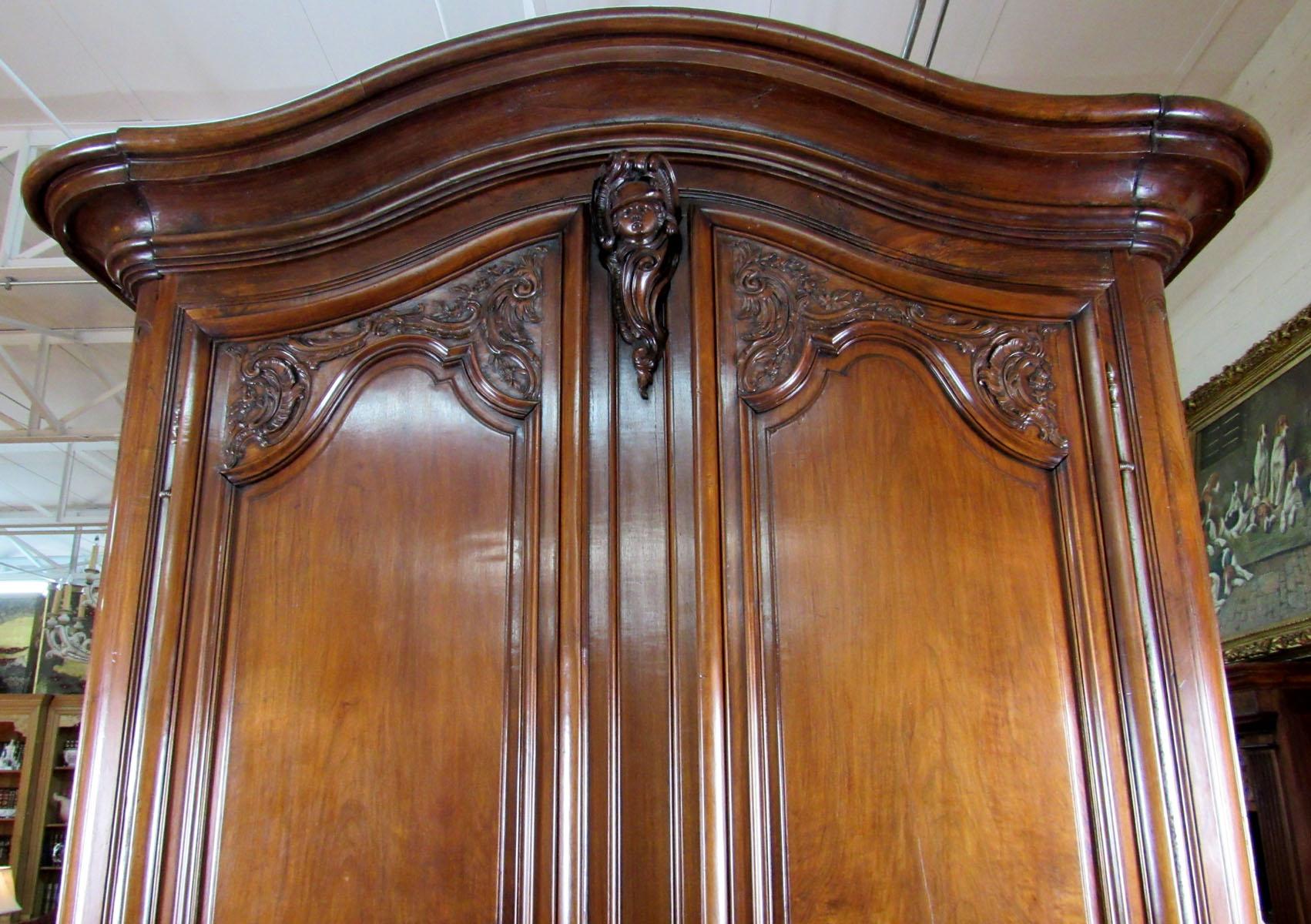 Louis XV period Bordeaux walnut armoire with soldier's head carved at the central crown.