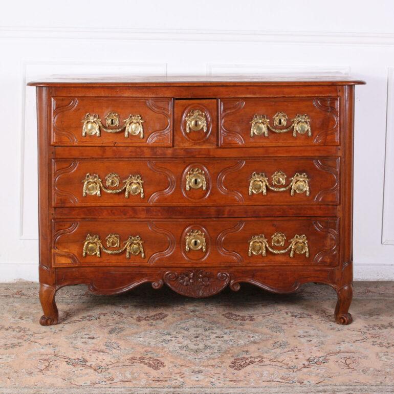 A walnut, Country French commode with three drawers above two long drawers, raised panels, and a nicely carved apron. Original bronze pull handles and escutcheons. Circa 1780. Serpentine Front.