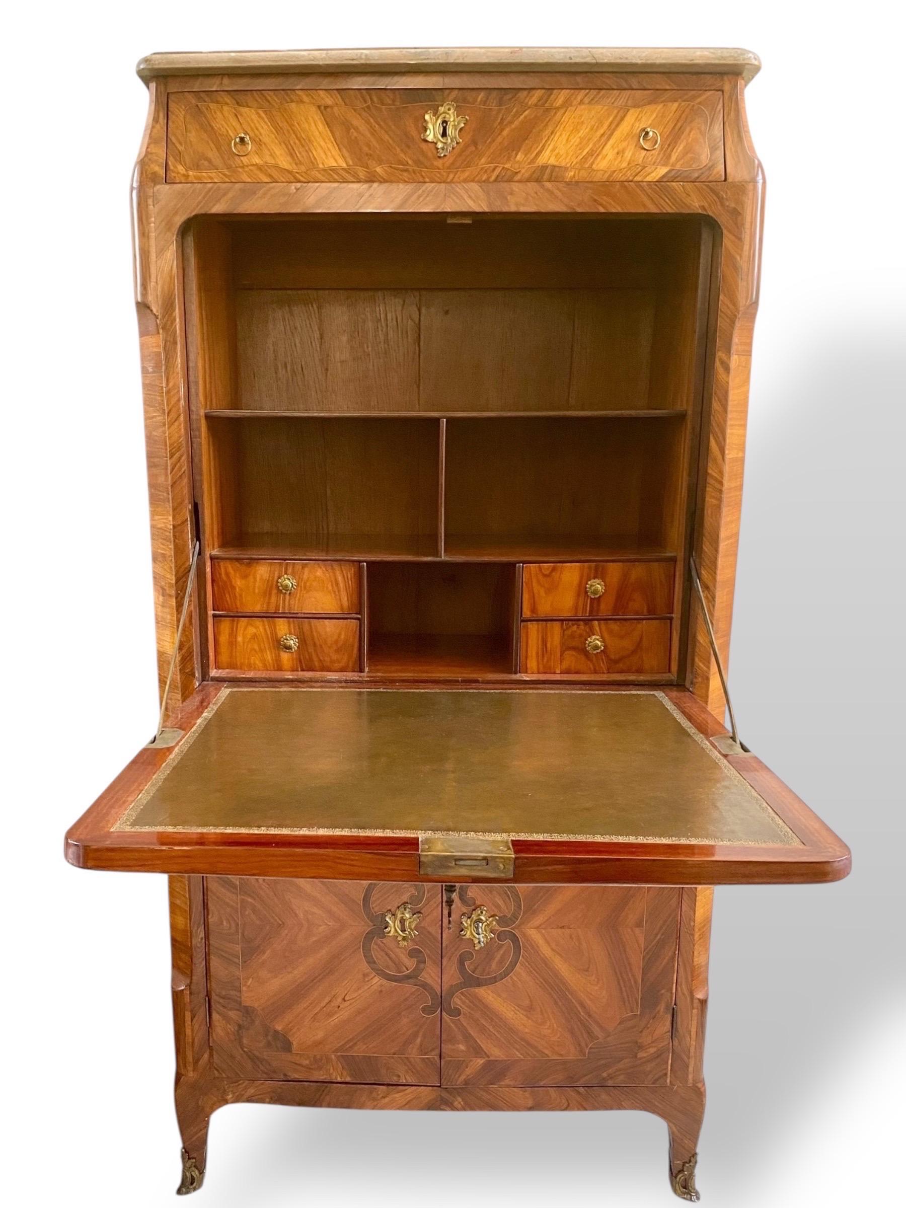 A very elegant and rare Louis XV period drop-leaf secretary desk, characteristic of Rococo furniture with its sinuous silhouette and refined proportions. The curved front rests on arched cabriole legs, finished with bronze sabots. The body is