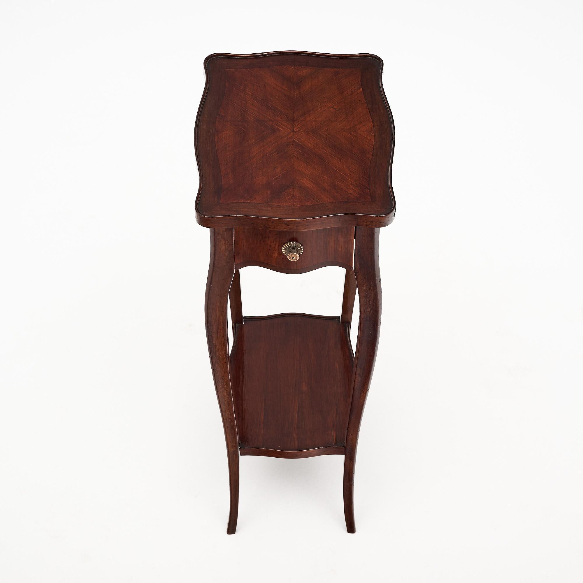 Petite French side table. Made of rosewood and finished with a lustrous French polish. The table features a dovetailed drawer with its original brass pull and a bottom shelf in between the four elegant cabriole legs. The piece is in very nice