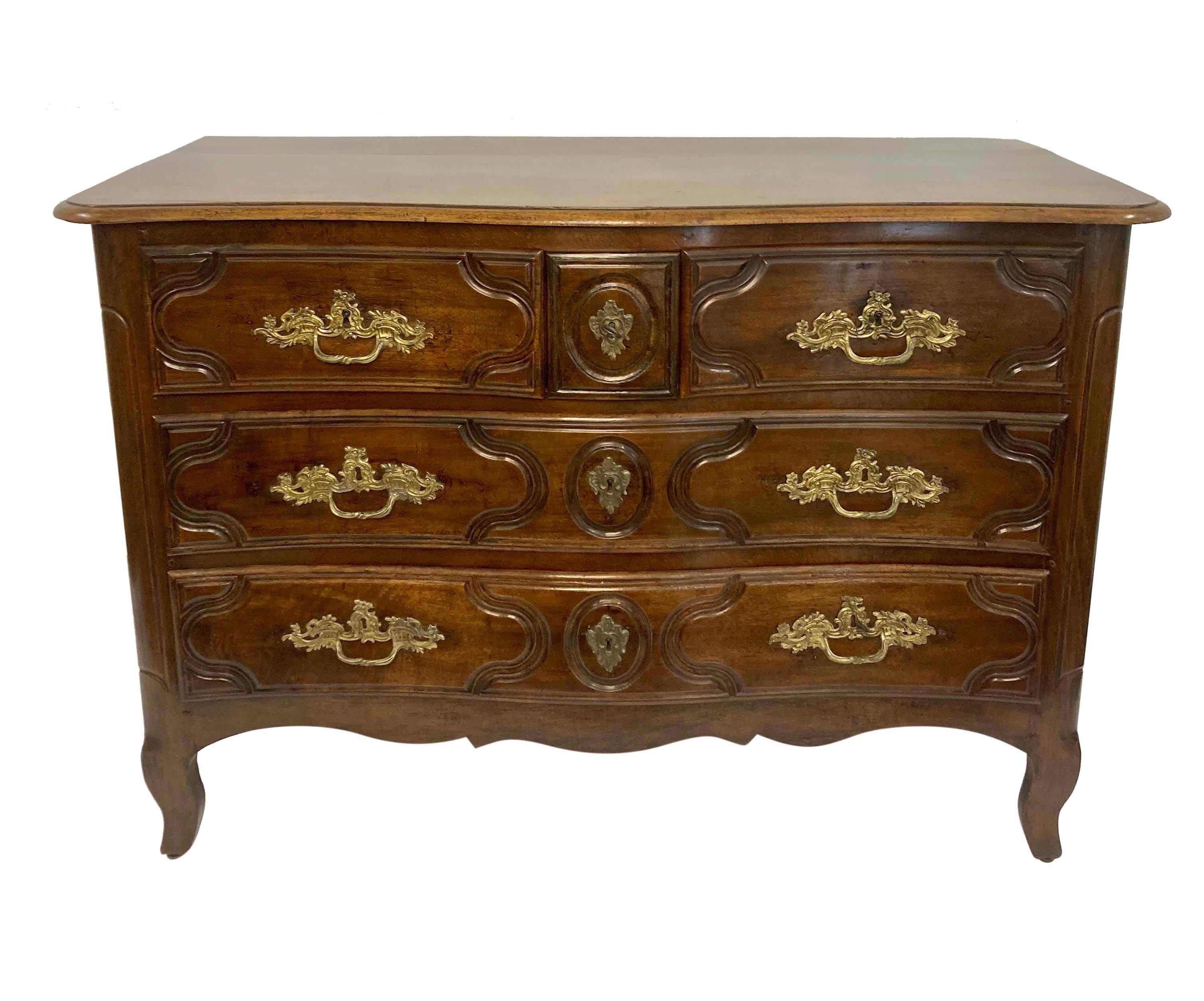 An XVIII Century French Louis XV walnut commode, with a serpentine front and five drawers. The original handles in gilt bronze, carefully restored with a great patina.