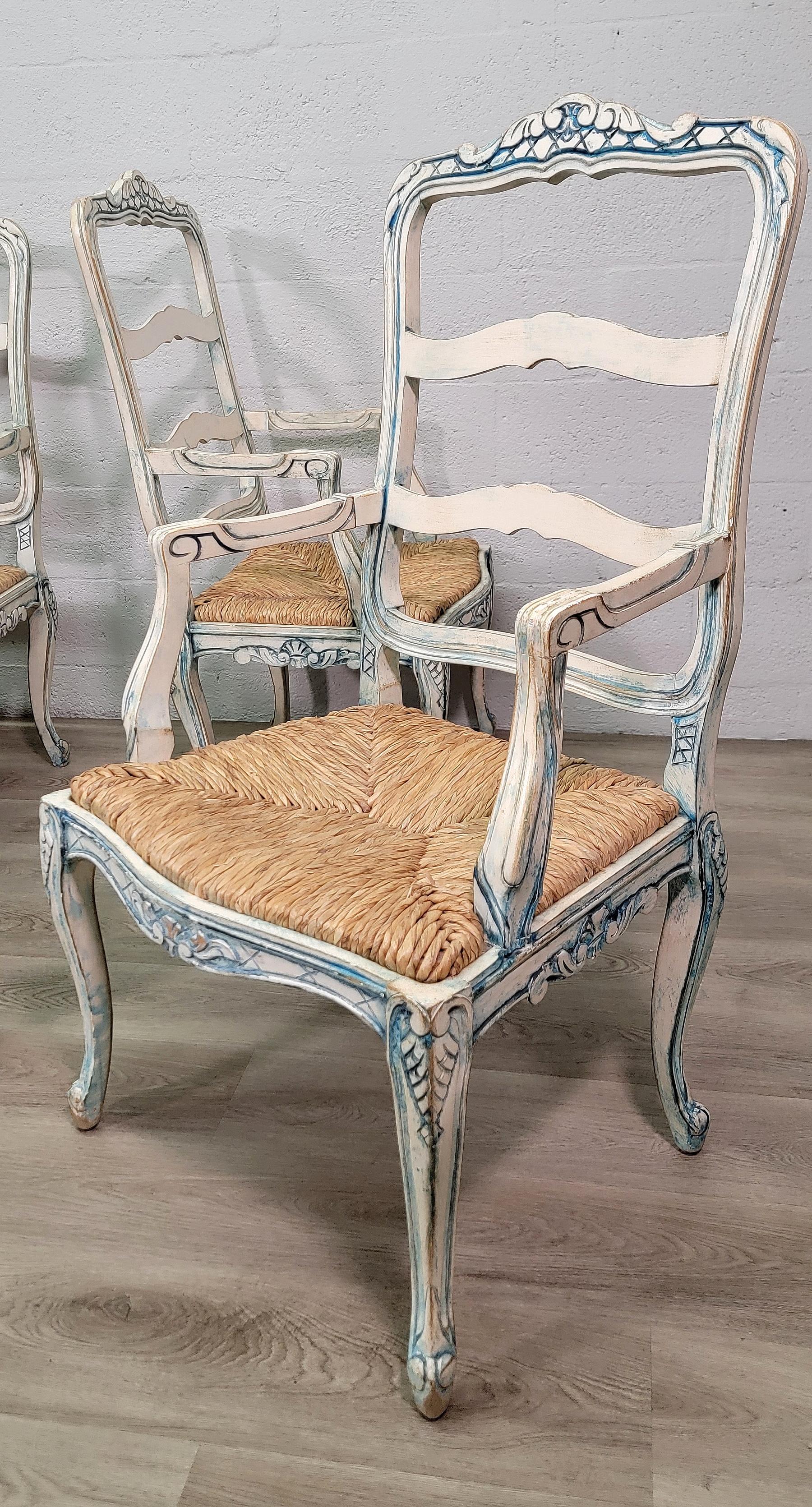 A set of four Louis XV provincial style white and blue painted dining armchairs, 20th century.
Standing on four cabriole legs with hand rush seat.
Serpentine form, ladder back frame with distressed blue painted decoration and white finished ground