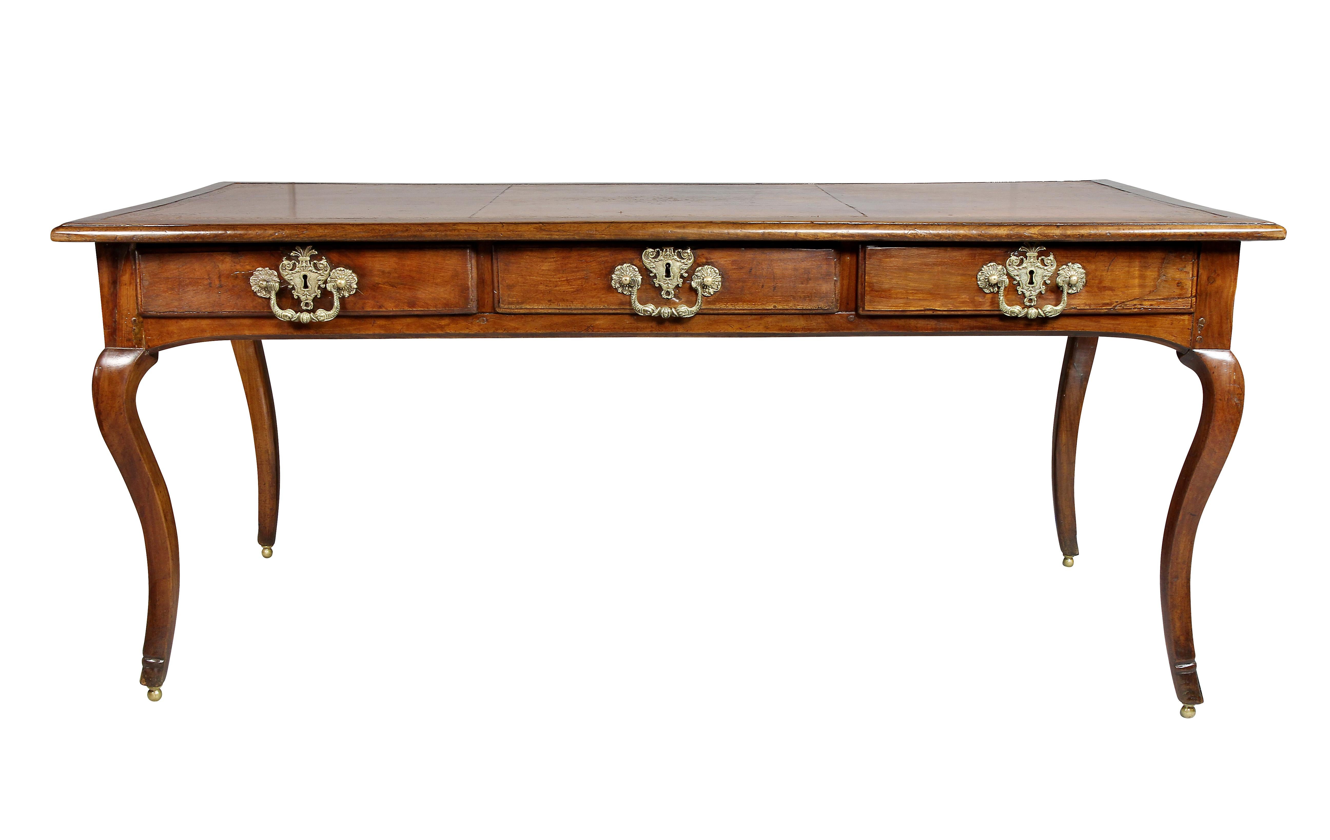 Rectangular top with original tooled brown leather with distressed sections over three drawers with elaborate bronze handles and false opposing drawers, raised on cabriole legs and brass ball feet.