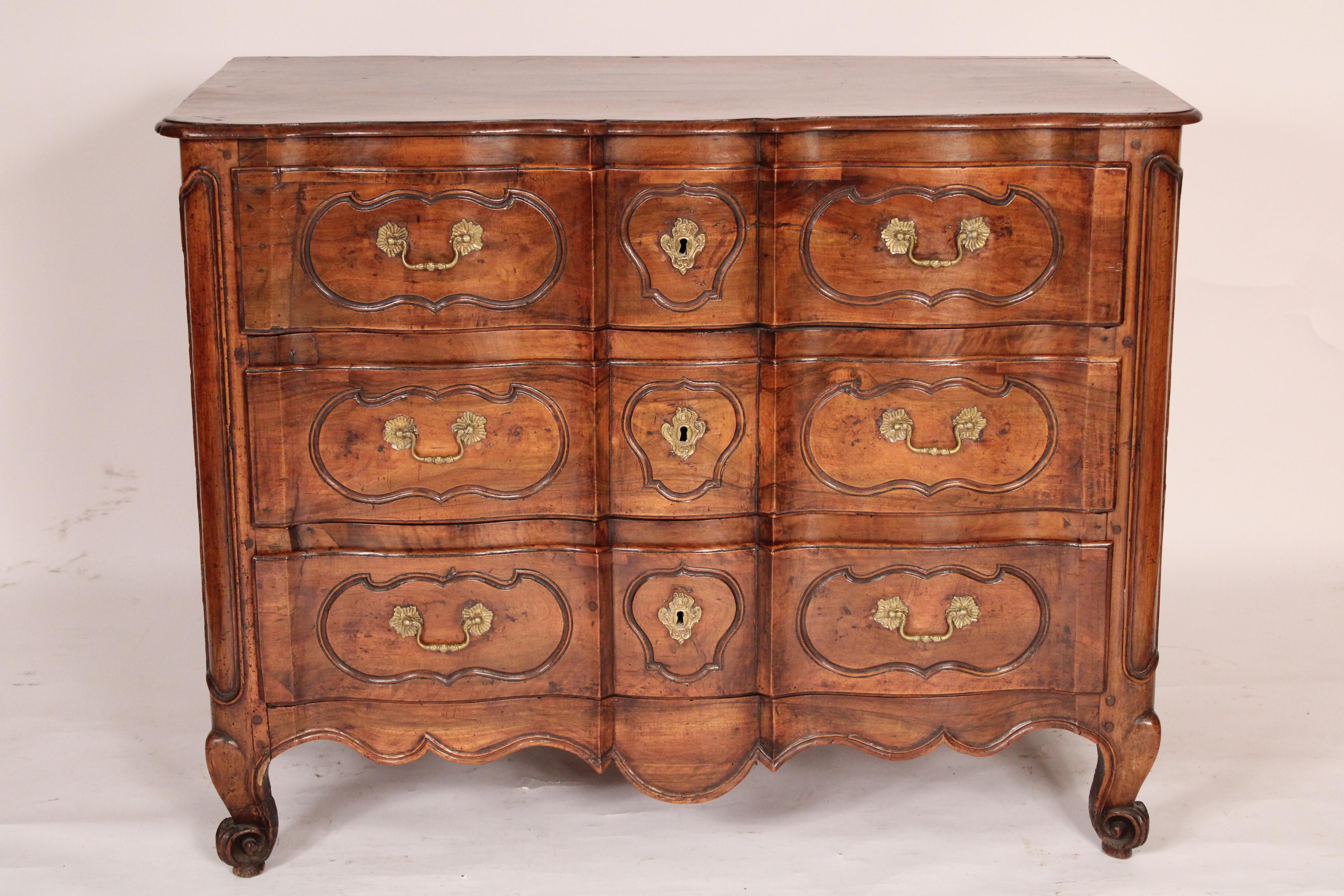 Louis XV provincial walnut 3 drawer chest of drawers, early 19th century. With an overhanging single board top with molded front and side edges, below 3 arbalete shaped drawers with brass pulls and escutcheons, a scalloped apron, resting on French