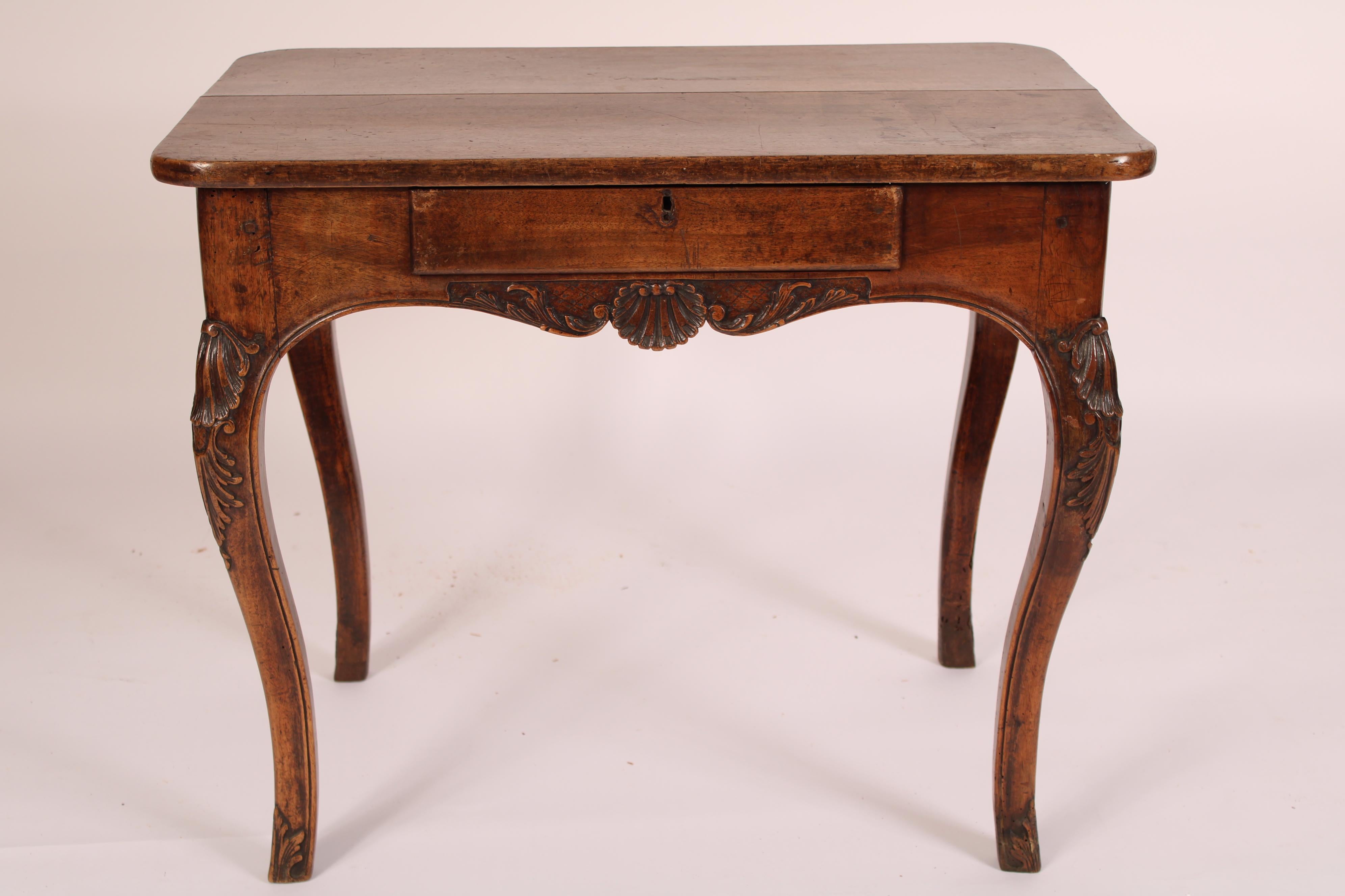 Table d'appoint provinciale Louis XV en noyer, fin du XVIIIe siècle. Avec un plateau en noyer à deux planches aux coins arrondis, un tiroir en frise, un tablier avec une sculpture centrale de coquillages sur le tablier à l'avant et à l'arrière, des