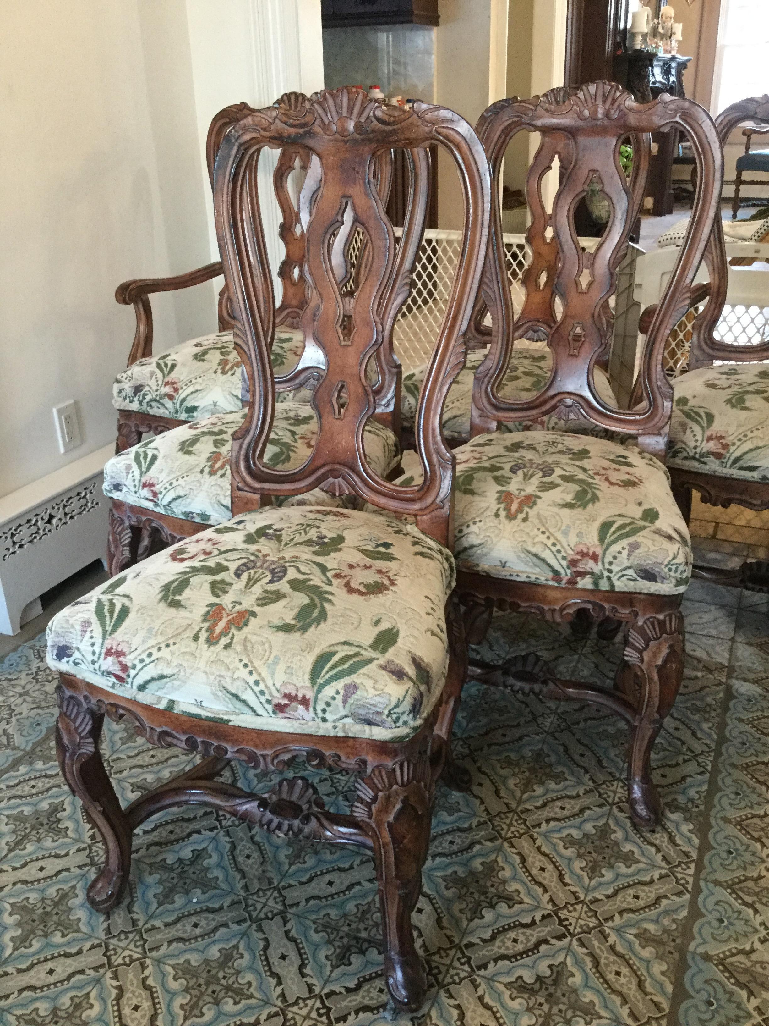 A remarkable vintage set of six Italian dining chairs handcrafted wood featuring four side chairs and two armchairs with grotto-style carved details throughout the entire frame. The seat is upholstered in a beautiful Chenile and rests on sturdy