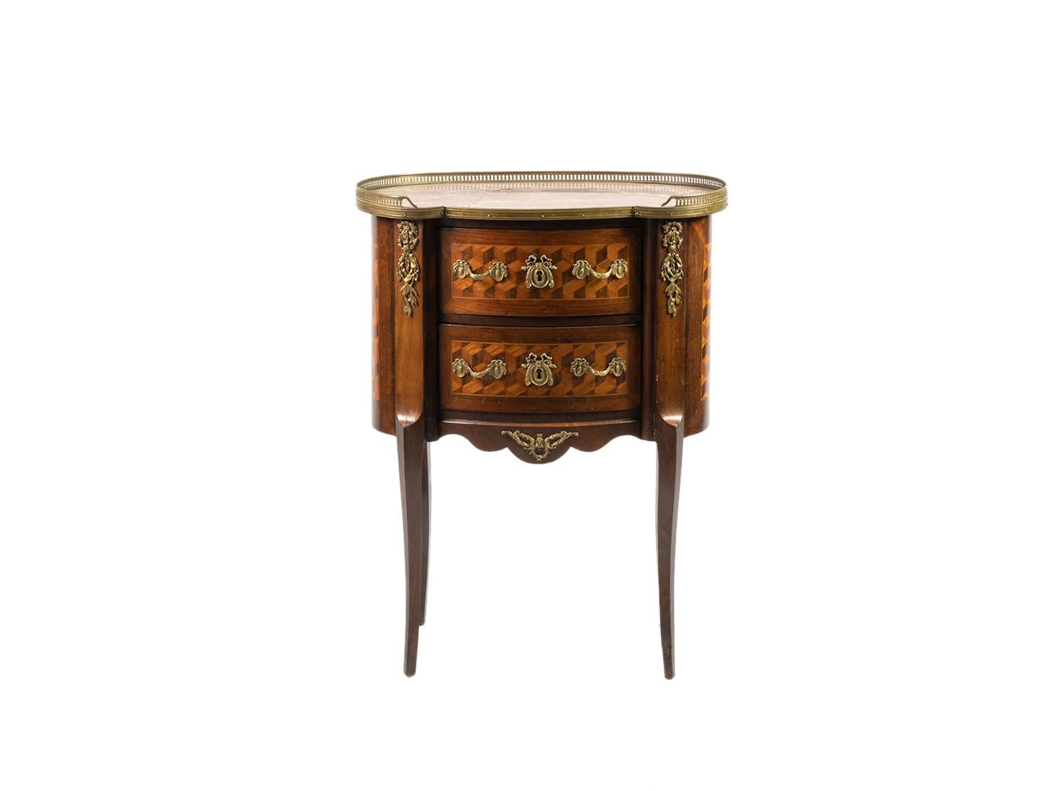 An oval shaped commode, a bedside type piece in transition between Louis XV and Louis XVI style.
Rosewood and Pau-rosa, three drawers, exquisite marquetry, gilded bronze hardware and friezes. 
With metal upper railings and inlaid pink Cedar Marble