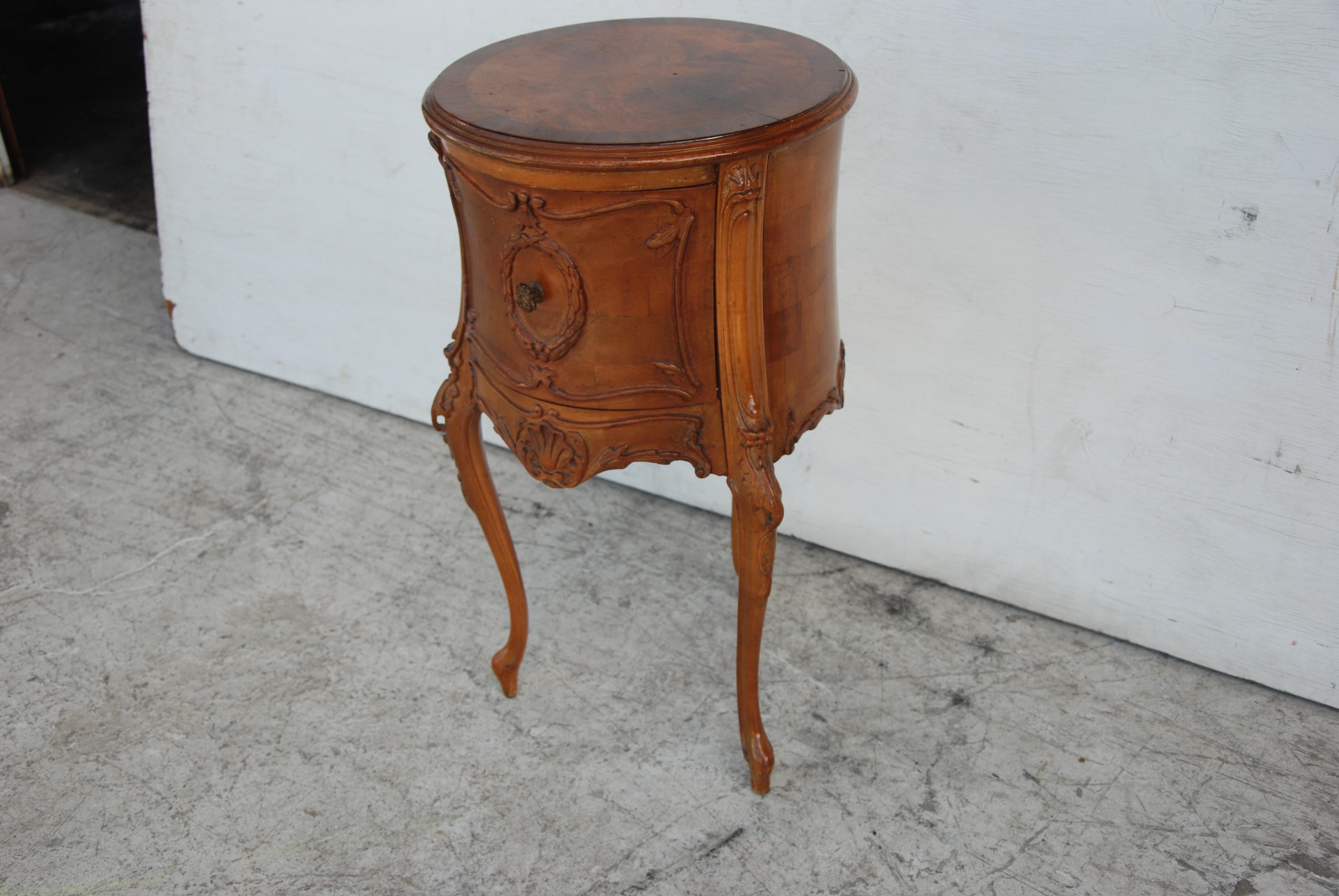 A round nightstand with a burl top, scroll and carved sides with single drawer on cabriole legs.


        