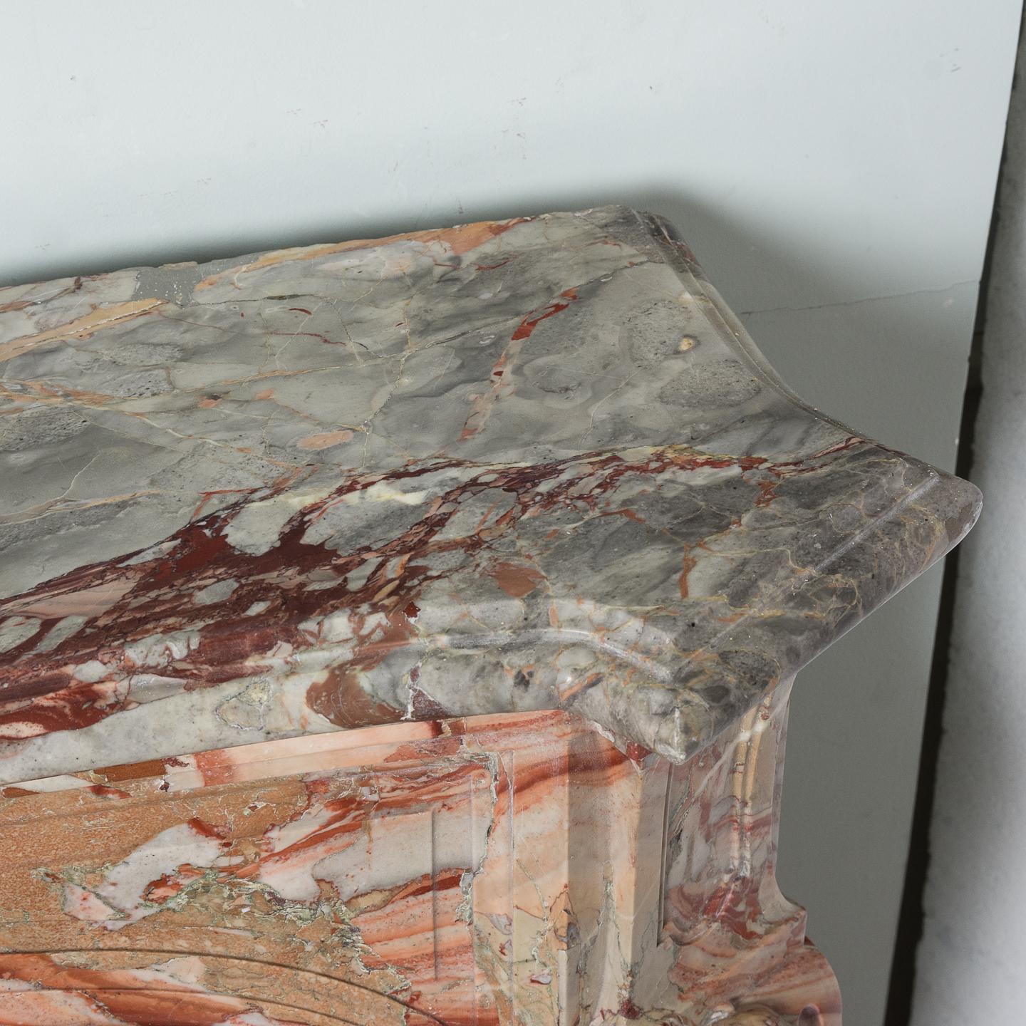 Louis XV Sarrancolin marble chimneypiece, 18th century, the shaped and moulded shelf above serpentine panelled frieze, the stop-fluted canted volute jambs headed by trails of bell flowers, on block-feet, with copper and brass interior. 

Copper