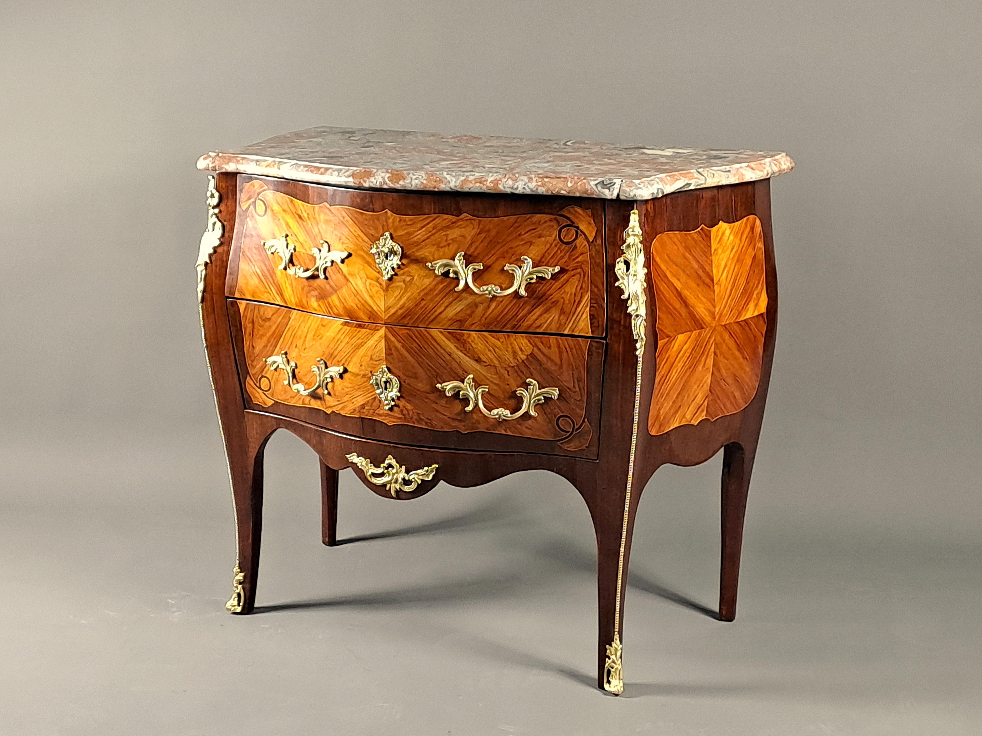Elegant Louis XV style commode in rosewood veneer with butterfly wing marquetry, fretted light wood frames with beautiful spandrels on the fronts, amaranth veneer in reserves.

Opening two drawers without crosspiece and topped with a beautiful