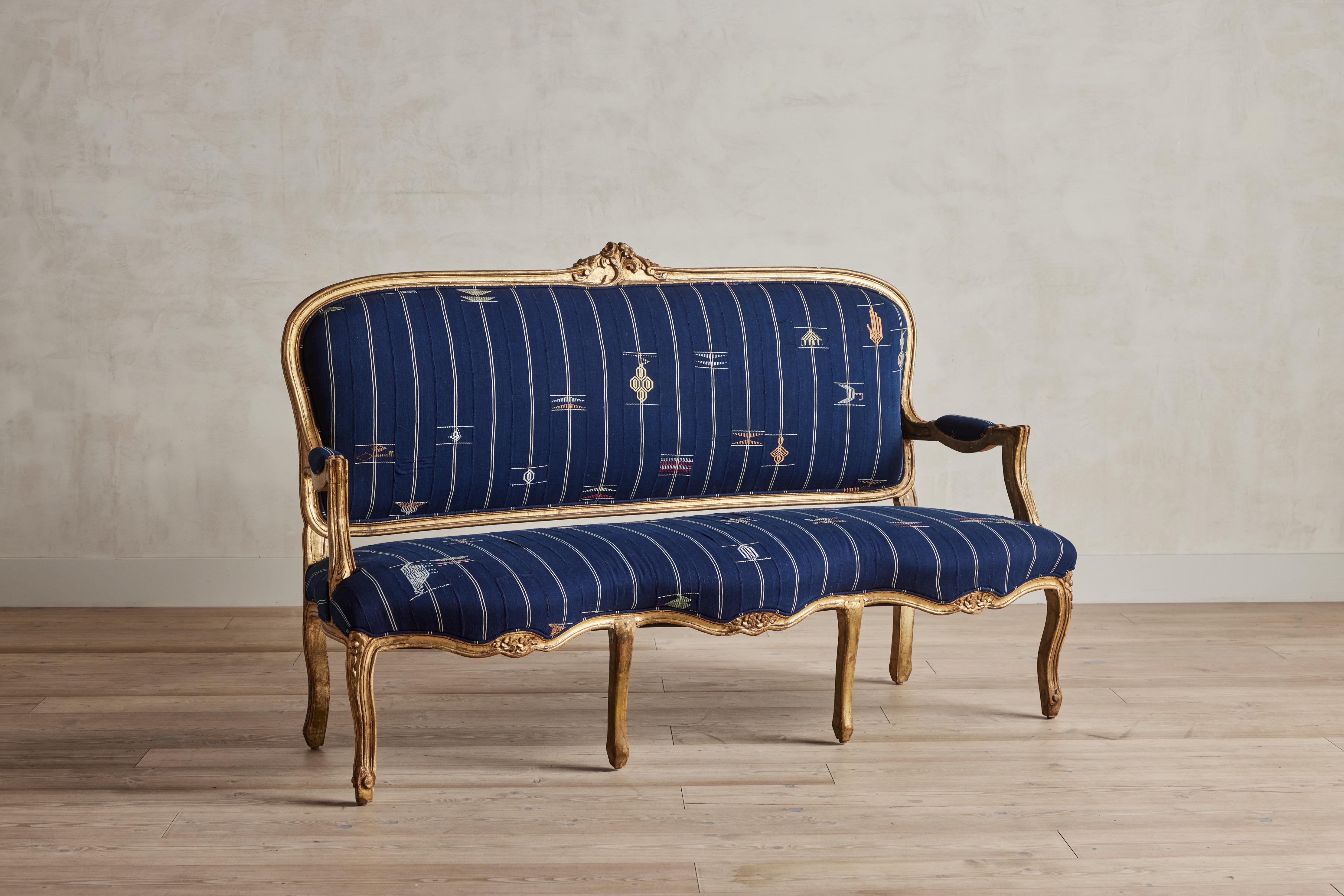 Louis XV settee from France reupholstered in a striking blue vintage Ewe textile from West Africa. Good condition with some wear on giltwood frame that is consistent with age and use.