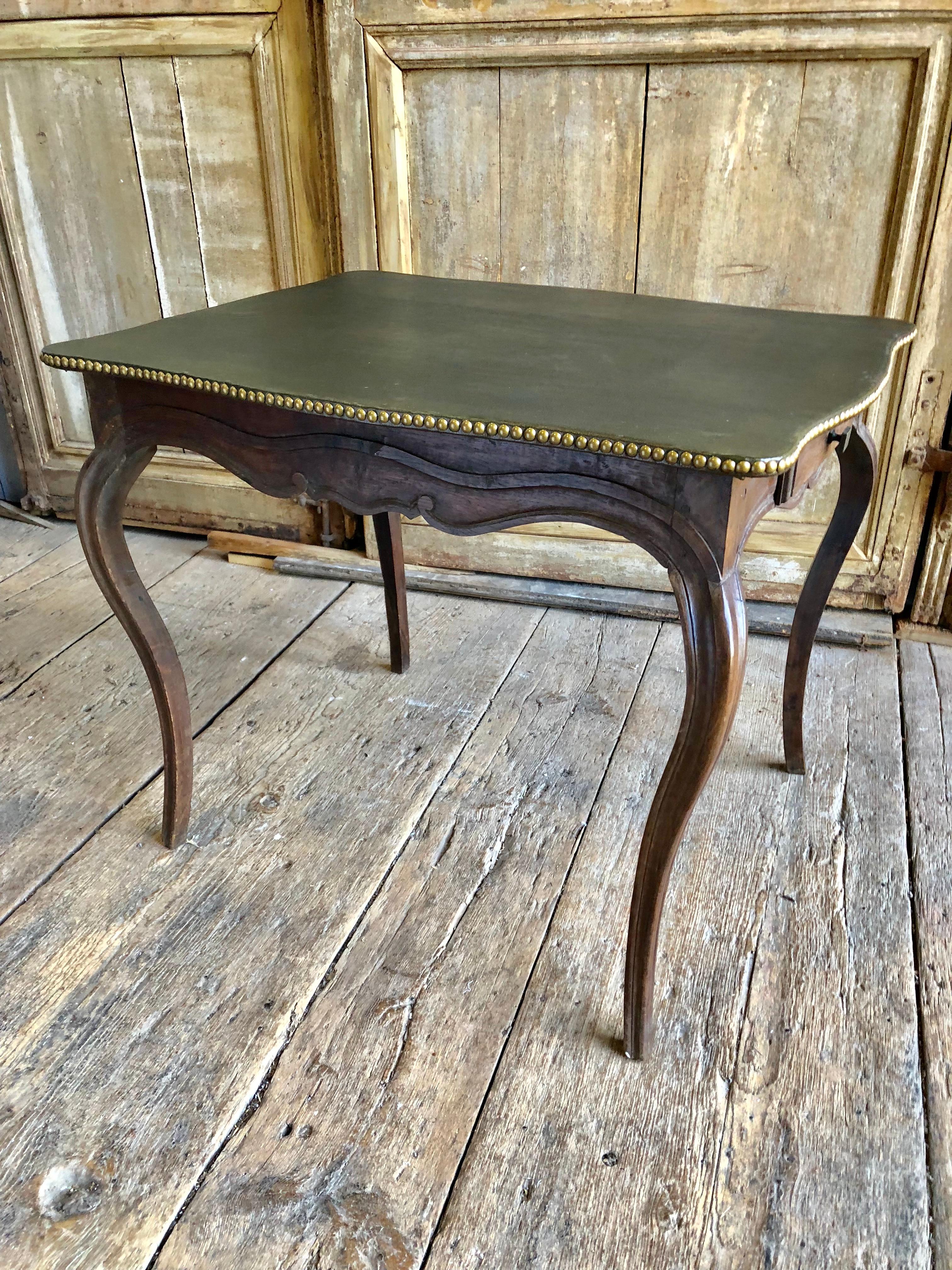 An 18th century leather-top side or card table circa 1780 in oak, with a dark green leather top with brass nail details, two small drawers in the scalloped apron on slender cabriole legs.