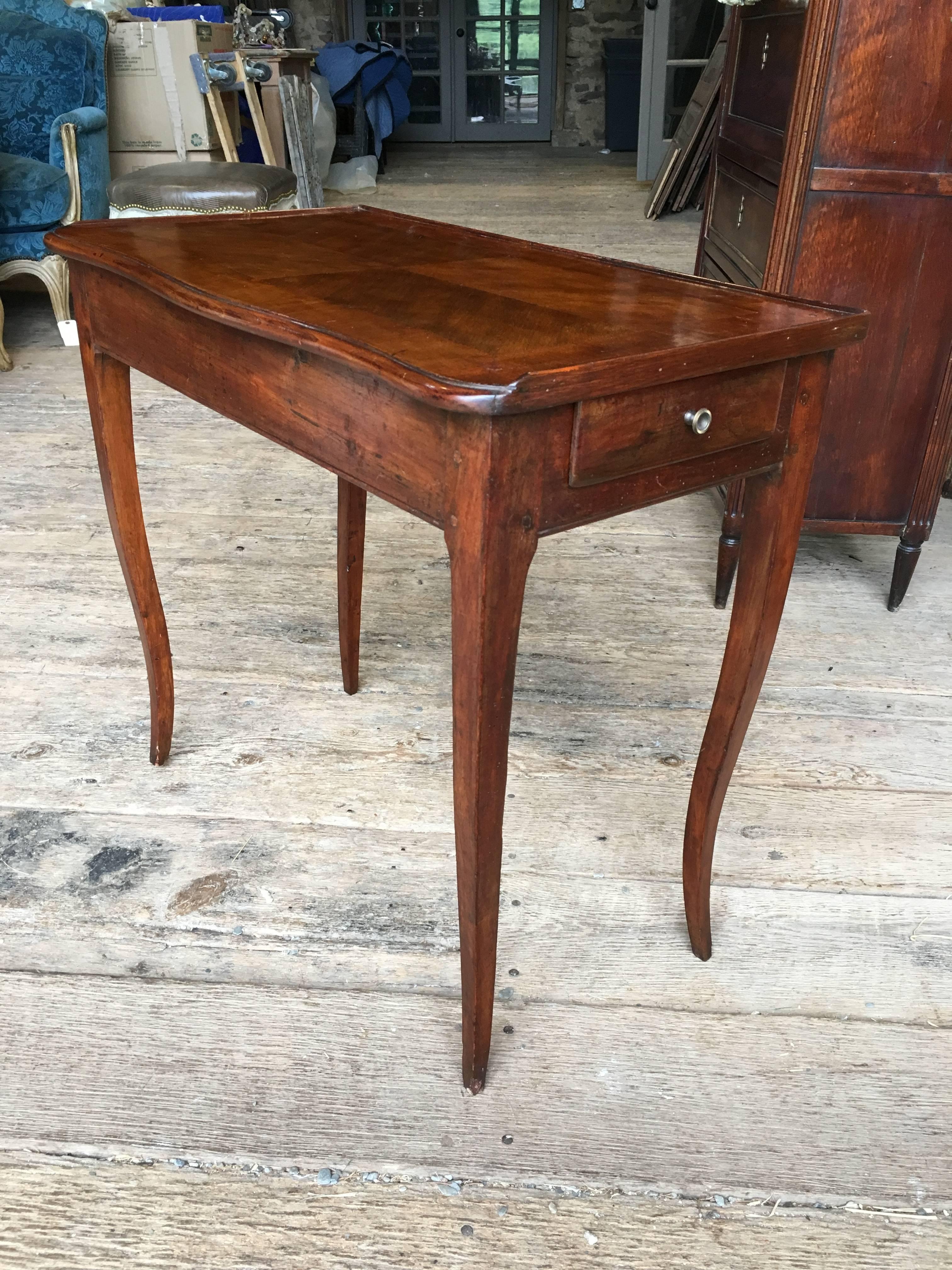 A petite Louis XV period side or writing table (table a ecrire) in stained pine and a parquetry top, with cabriole legs and a small drawer in the apron, French, circa 1780.