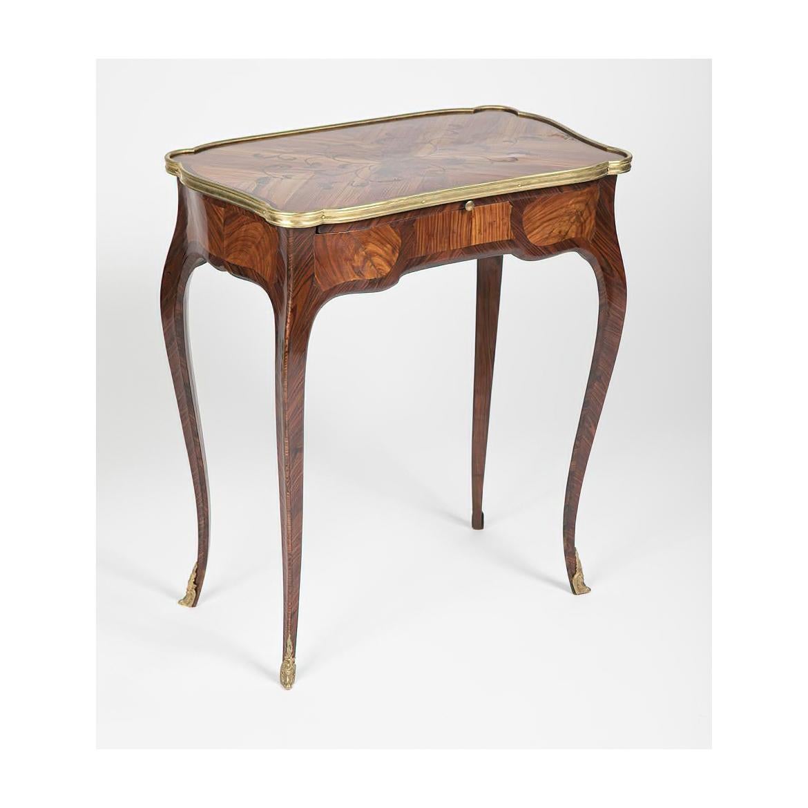 A French Louis XV marquetry inlaid side table with bronze mounts, a leather-lined slide-out writing surface and drawers on cabriole legs with bronze ormolu sabots.