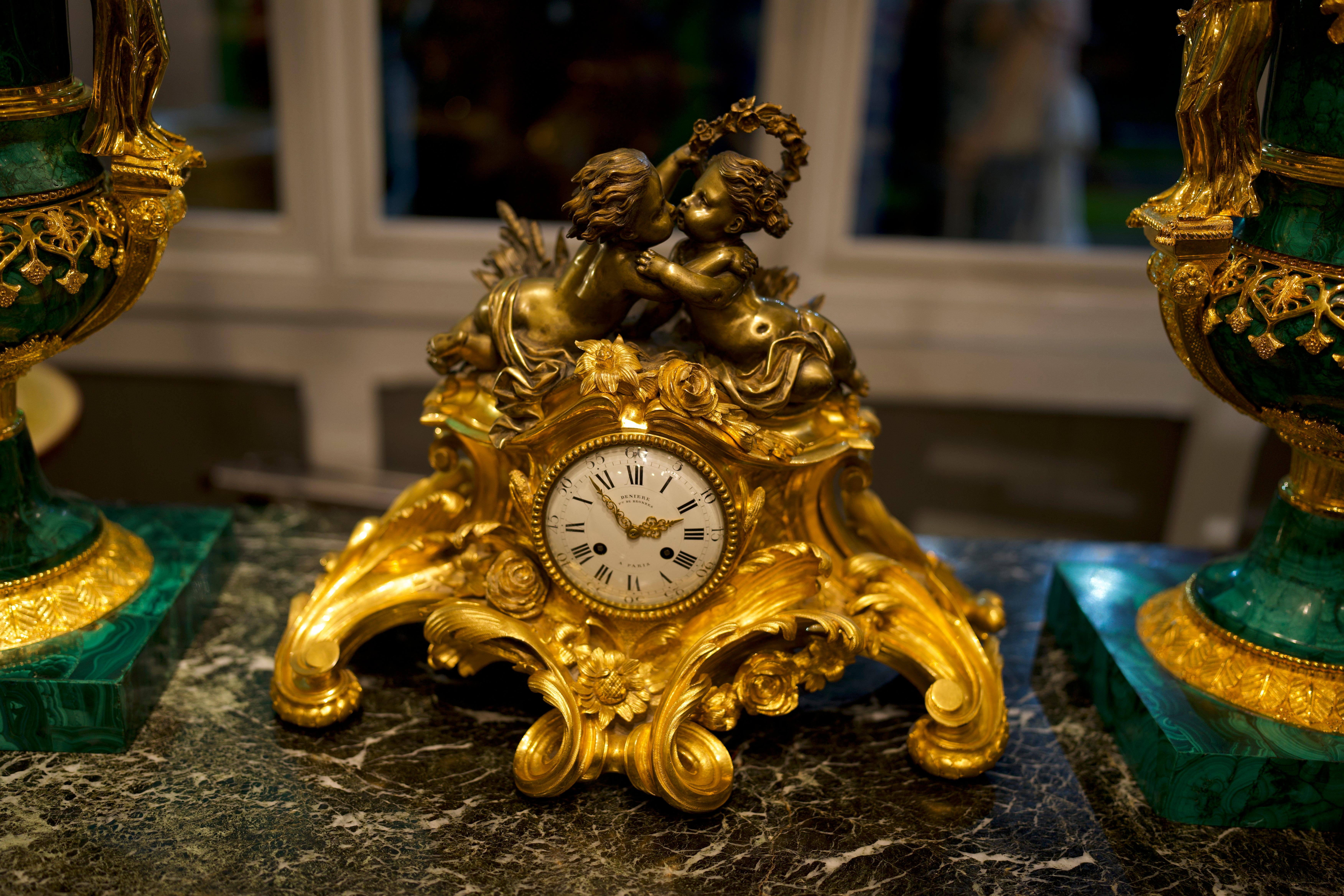 Louis XV style 19th century French figural gilt bronze mantel clock.

The enamel dial with Roman numerals and foliate pierced gilt hands. Signed Deniere A Paris. Mounted with two bronze cherubs kissing, the piece expresses an elegant design,