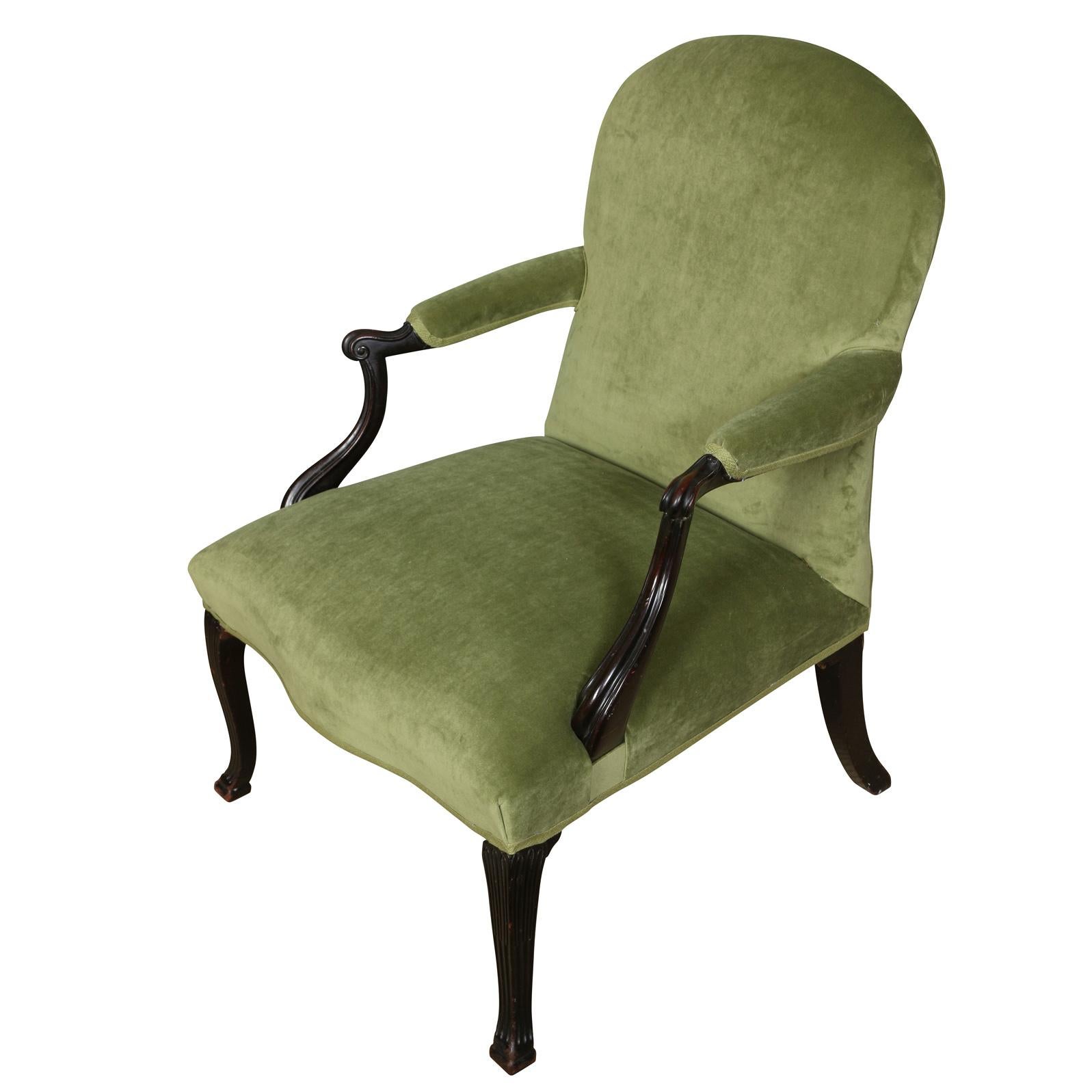 A vintage Louis XV style arm chair with a rounded back and seat front, newly reupholstered in green velvet. Velvet wraps around the entire seat, chair back and arm rests. Arms end in carved scroll form. Cabriole legs and arms are both carved with a