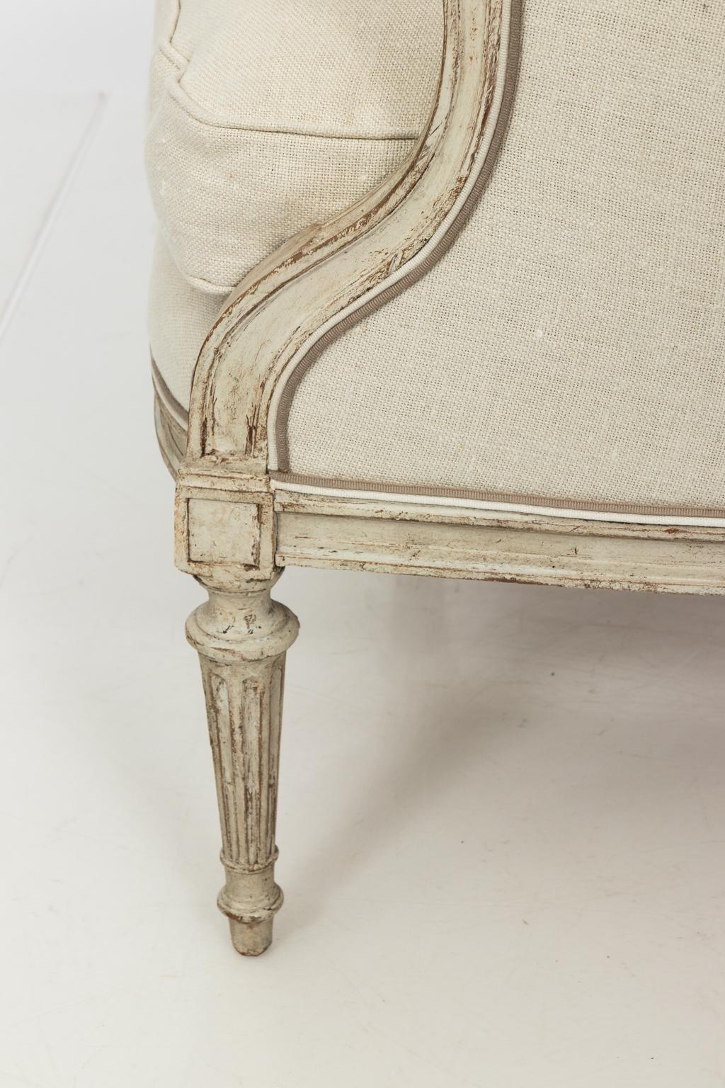 White painted bergere chair from France with curved, fluted trim back and custom white upholstery, circa 19th century.
 
