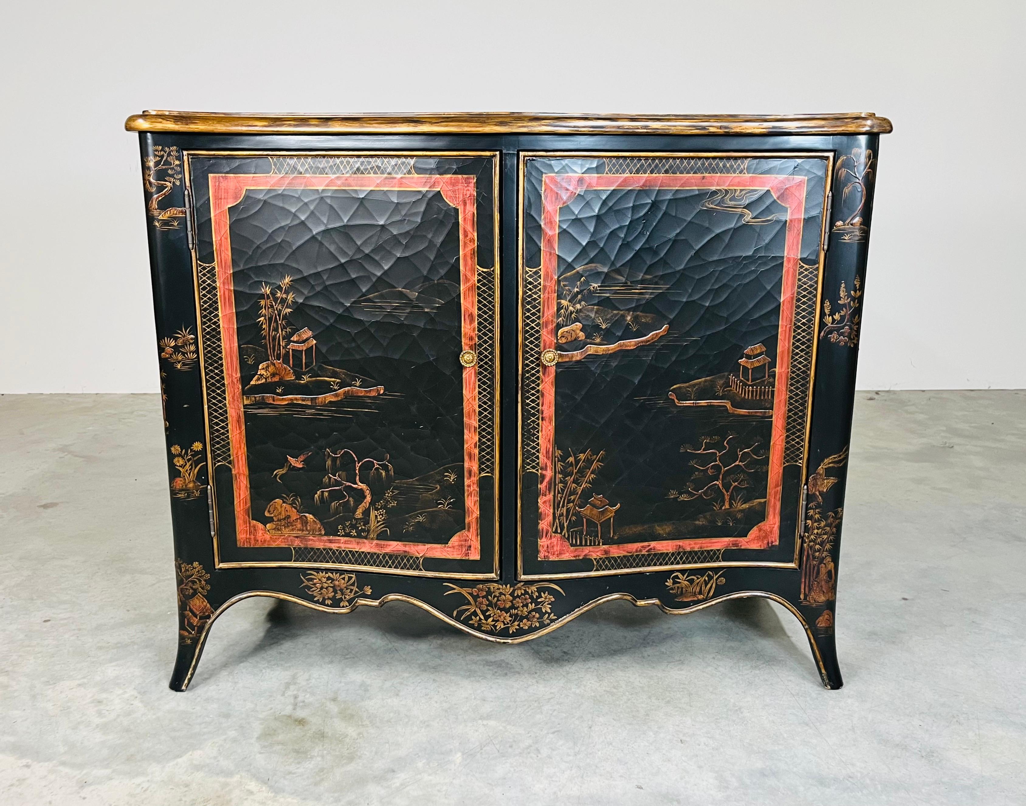A beautiful Louis XV style Chinoiserie buffet having black crackle effect finish with hand painted scenery throughout and gold edging by Maitland Smith. The interior features ample storage with 2 sections each having height adjustable shelves behind