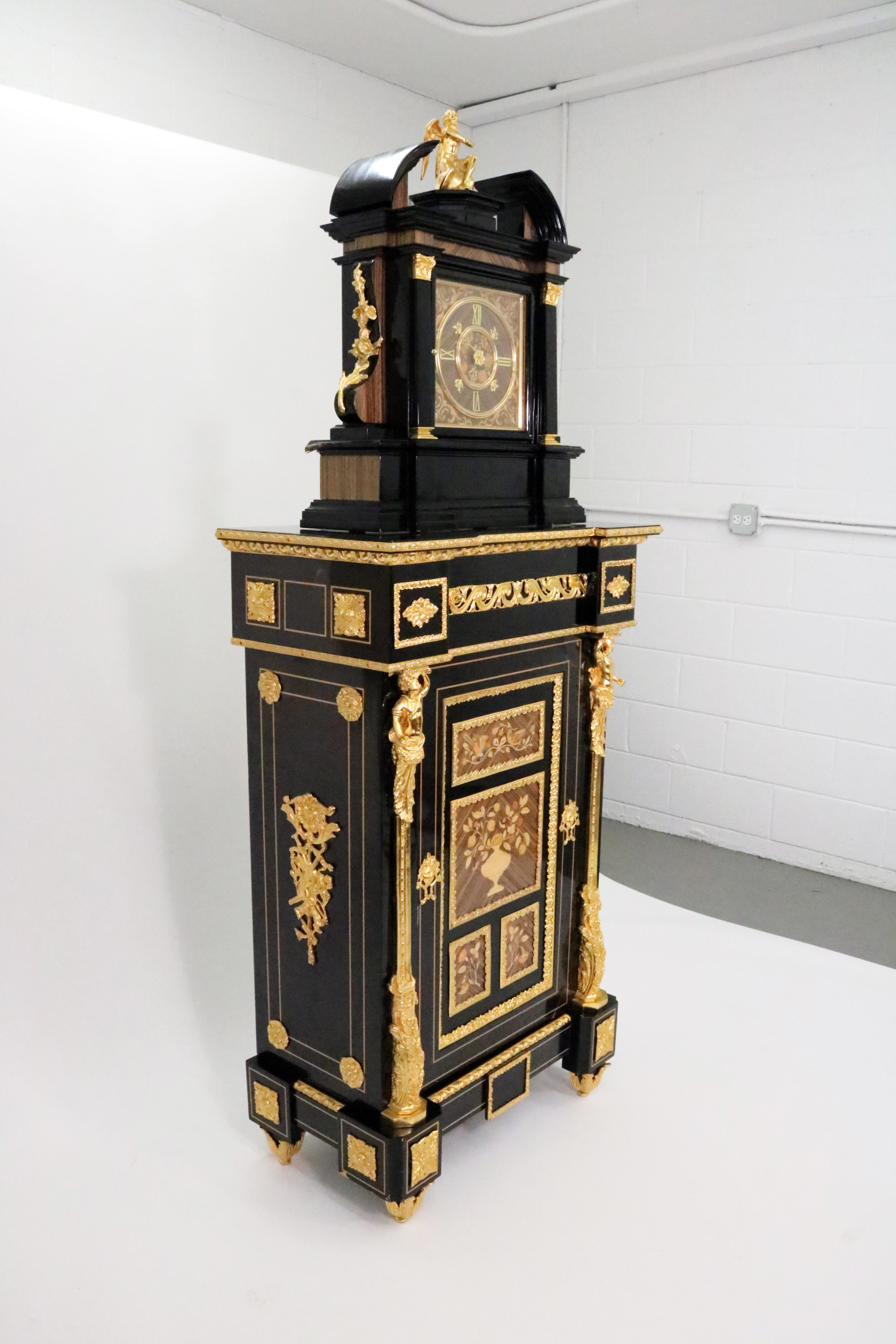 A grand longcase clock produced in Italy in the 1970s in a rococo Louis XV style with dore bronze ormolu mountings and wood inlay decorating a black-lacquered wood case.

The German-made clock’s two-barrel spring movement is a Hermle calibre