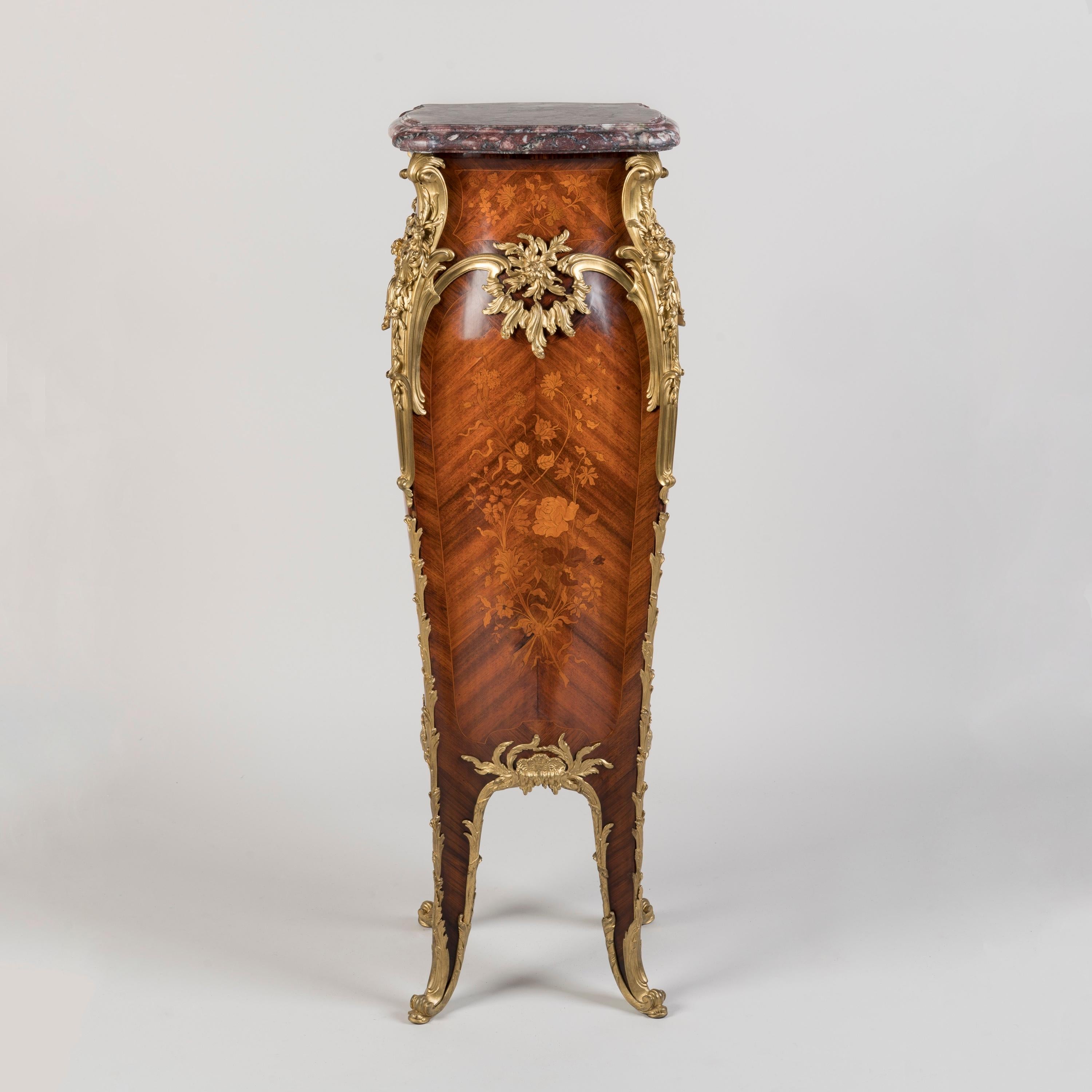 A Marquetry-Inlaid Pedestal in the Louis XV Style
Index no. 184

Of elegant bombé form with bookmatched kingwood crossbanding and floral marquetry to all sides on a bois satiné ground, the corners dressed with foliate scrolling ormolu mounts