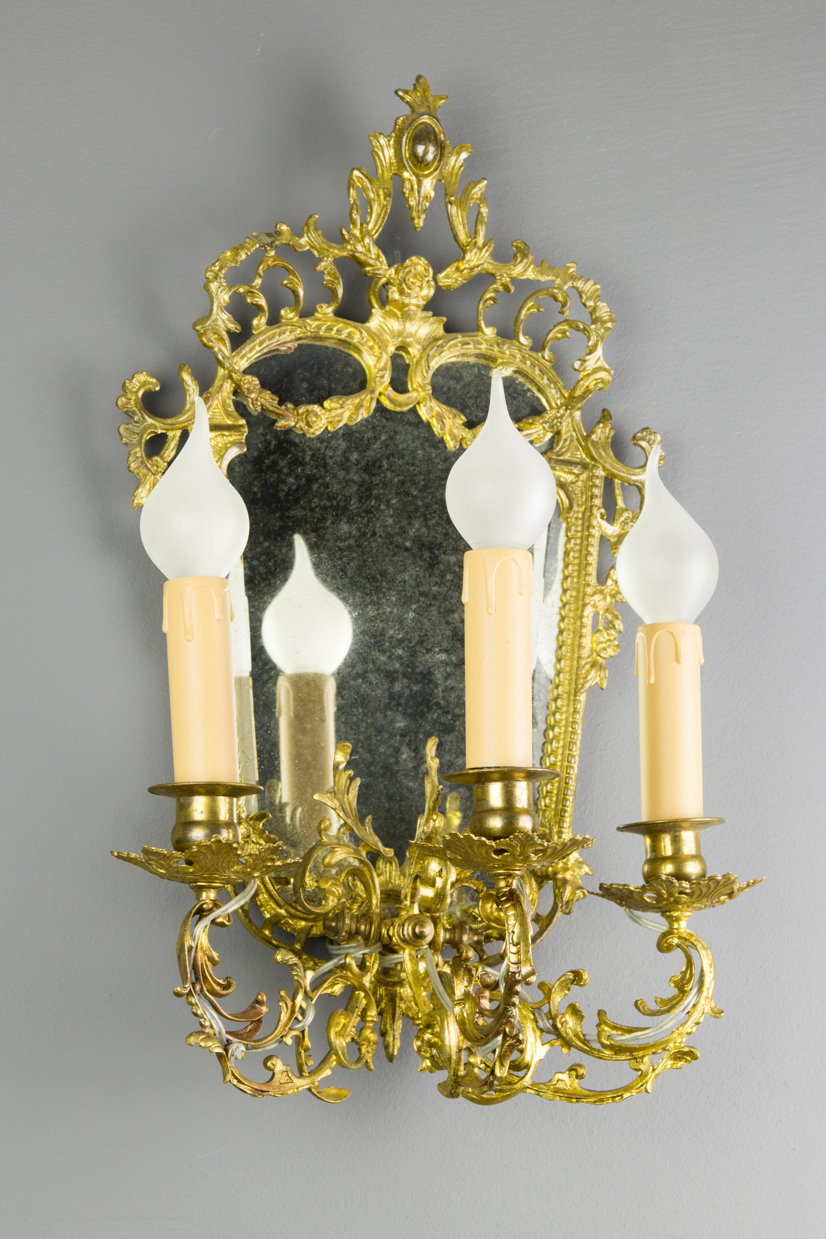 Schöne Louis XV Stil Messing und Bronze Girandole, Wandleuchte mit abgeschrägten Spiegel. Drei Arme, jeder mit einer Fassung für eine E14-Glühbirne, verziert mit Blattranken und Blumen, Frankreich, 1920er Jahre.
Abmessungen: Höhe 45 cm, Breite 30