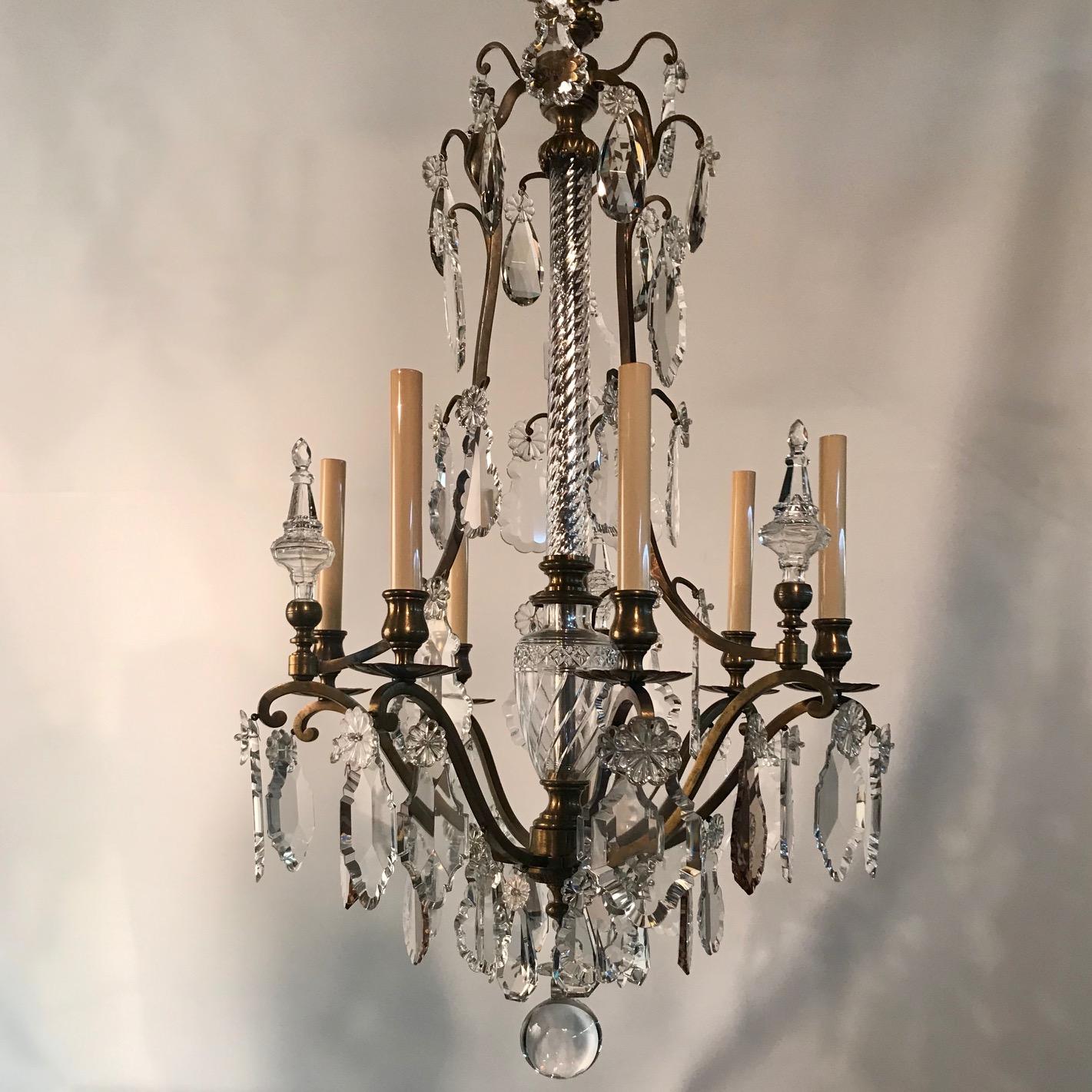 This elegant chandelier has a most unusual stem, the lower part is vase-shaped and cut; the upper is clad with wrythen molded glass very much reminiscent of Baccarat. It is tastefully dressed with cut spires and violin pendants both clear and