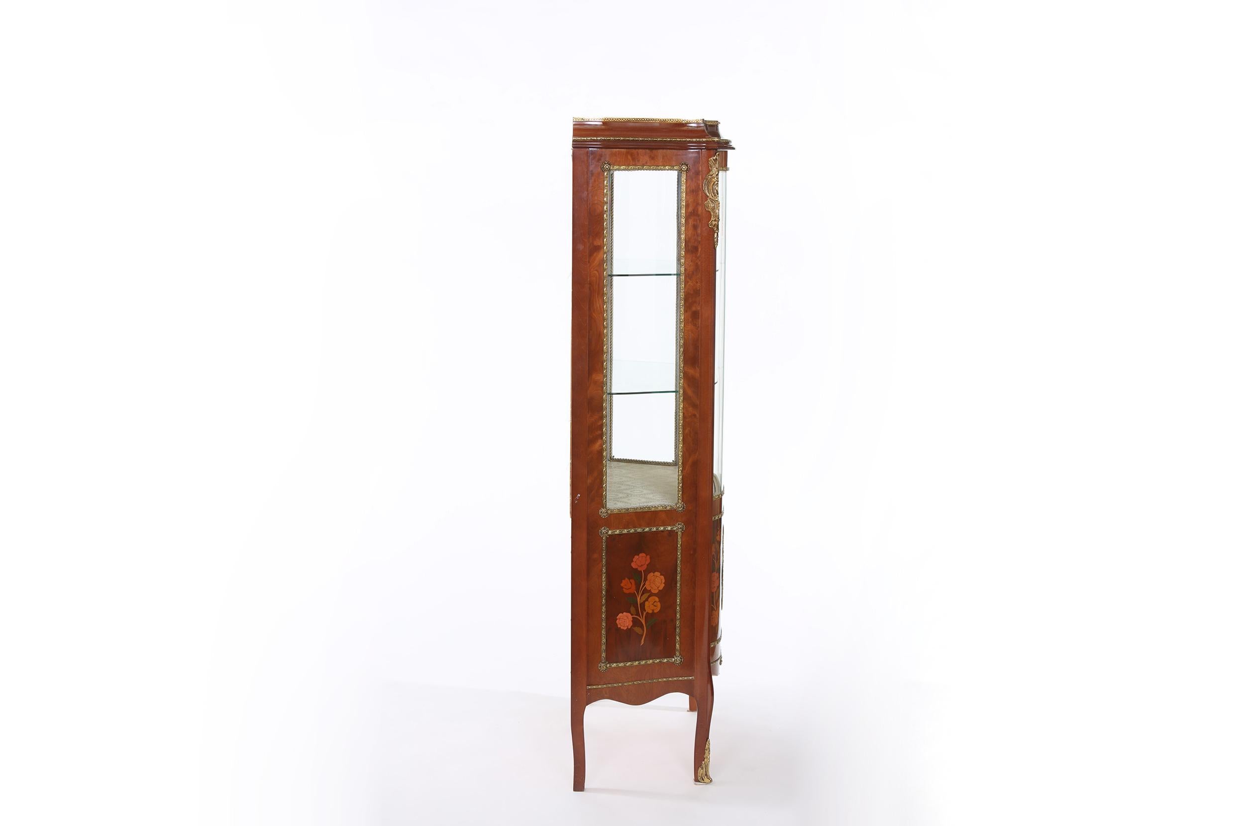 Louis XV style bronze mounted China display cabinet / vitrine with exterior inlaid design details. The interior of the cabinet has two glass shelves and lined with gold patterned brocade. The cabinet stands on cabriole legs with ormolu mounts. The