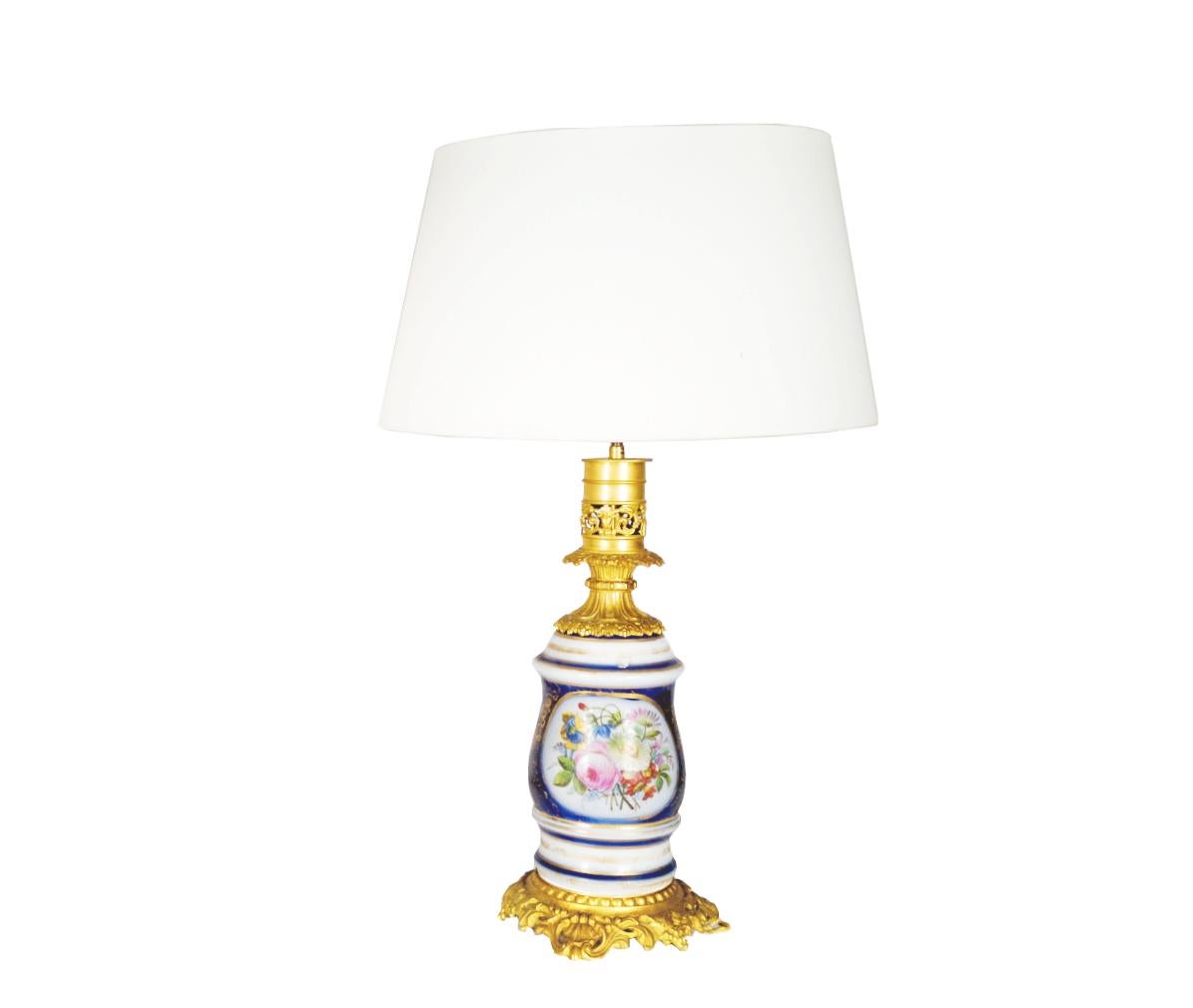 Lámpara de mesa de porcelana con motivo de ramo de flores de Sevres y bronce dorado decorado con una corona dorada sobre feuillagée.
Cable eléctrico dorado trenzado. En condiciones de trabajo.

Altura sin pantalla: 48,5 cm