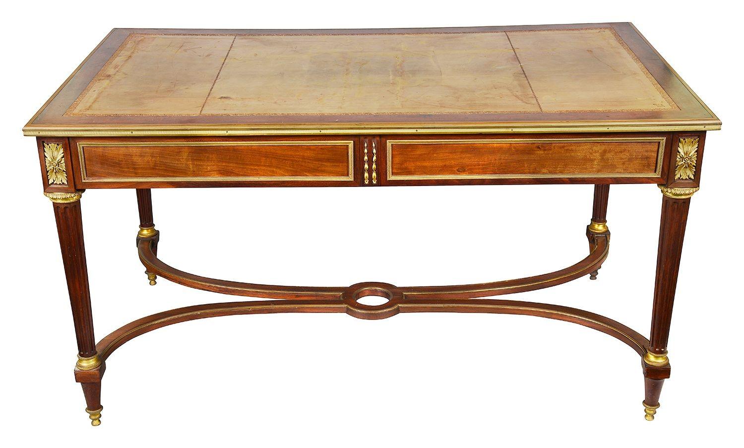 This late 19th-century French bureau plat is a stunning example of mahogany craftsmanship. The piece features a rich mahogany finish and an elegant inset leather top, enhancing its sophistication. With two spacious drawers adorned with intricate