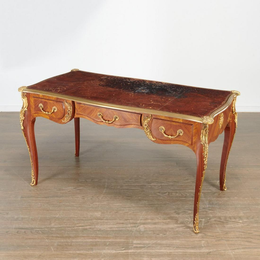 Louis XV style ormolu mounted kingwood bureau plat, 19th c., France, the shaped top with inset tooled leather and bronze rim, over three frieze drawers and faux-drawers on the reverse, the case veneered in chevron-pattern marquetry, the sides