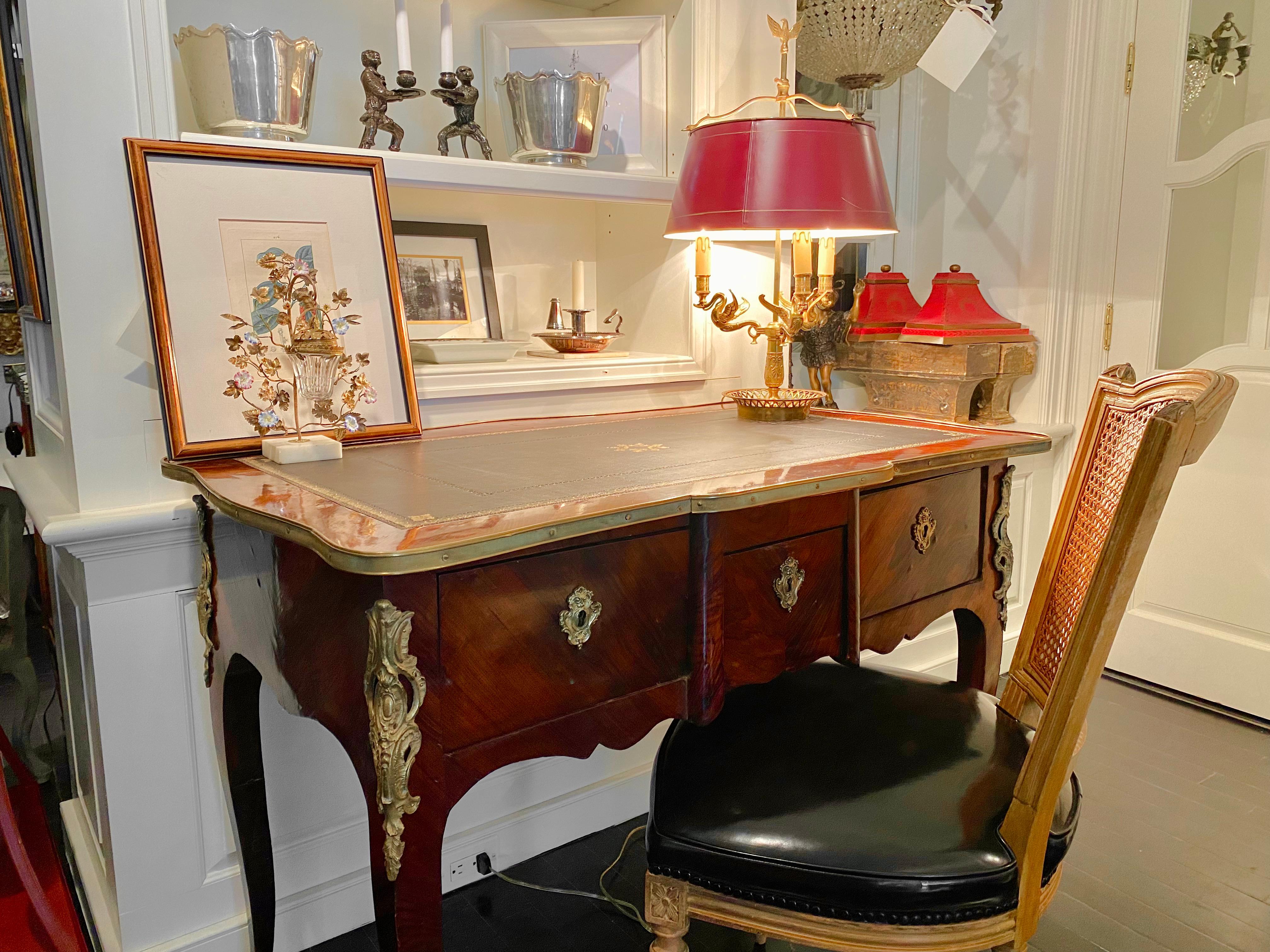 Ancien bureau plat de style Louis XV, en bois de rose et monture Ormulu, reposant sur des pieds cabriole. Dessus en cuir travaillé.

Dimensions : 43