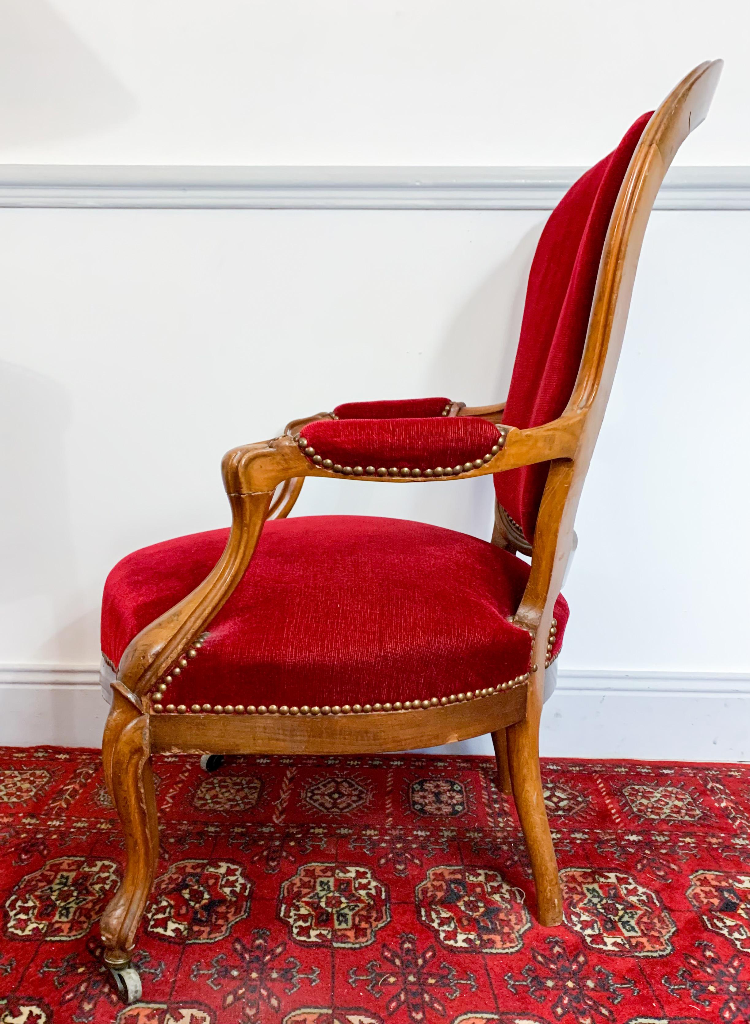 Nice Louis XV style walnut cabriolet armchair from Louis-Philippe period. Its front legs, resting on weels, are curved and end with casters. The armrests have volutes bringing a certain elegance. 
It has a beautiful red velvet tapestry. 
France