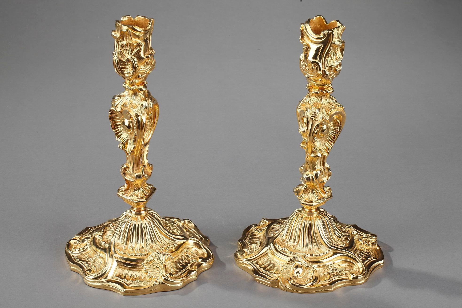 Pair of gilt and chiseled bronze Louis XV style candlesticks. The stem of each candlestick is sculpted with abundant foliage and intricate ribbing, spiraling upward to support the nozzle which is also embellished with lively foliage. Each